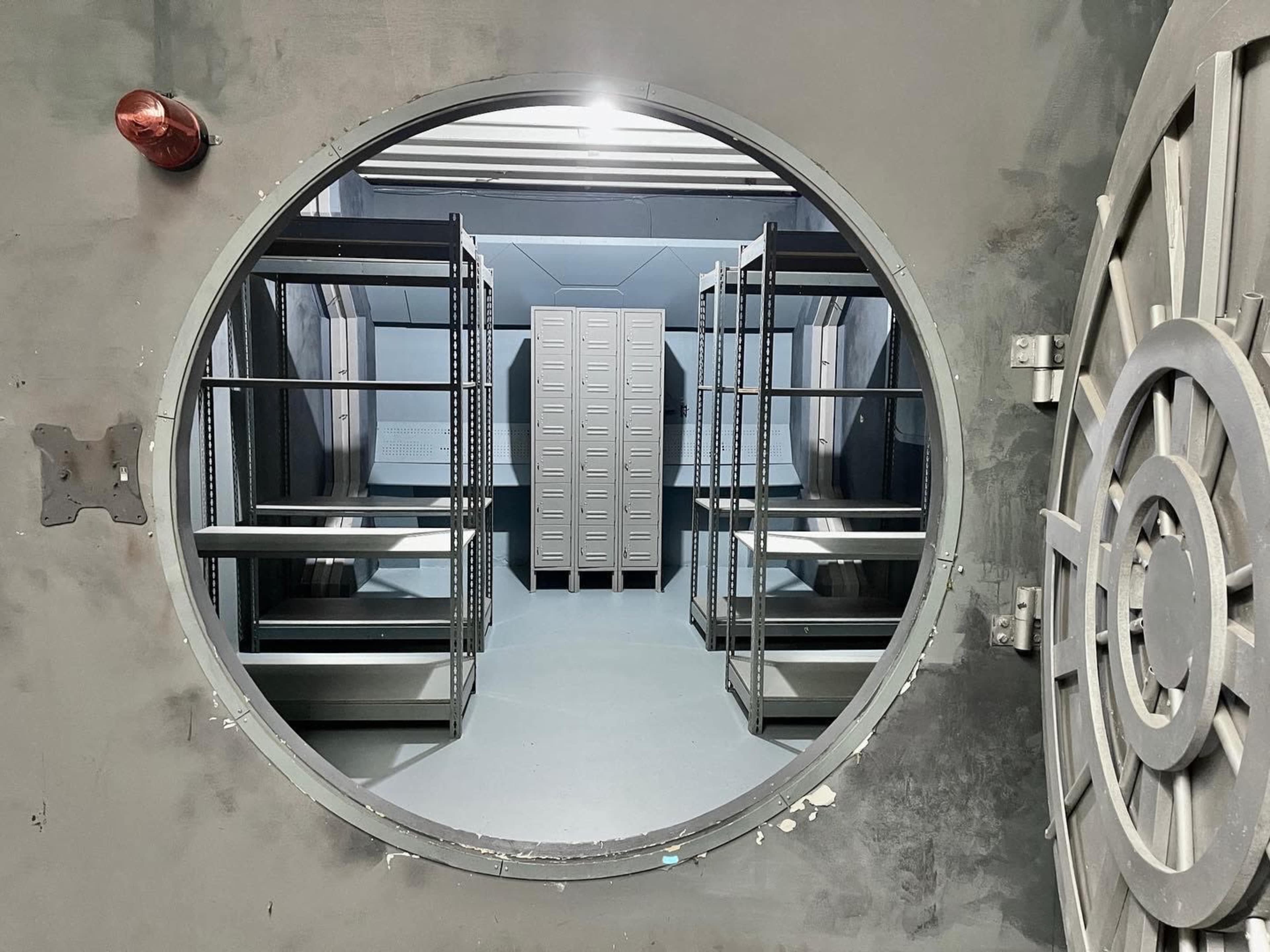 A circular doorway leading into a room with metal shelving units and lockers.
