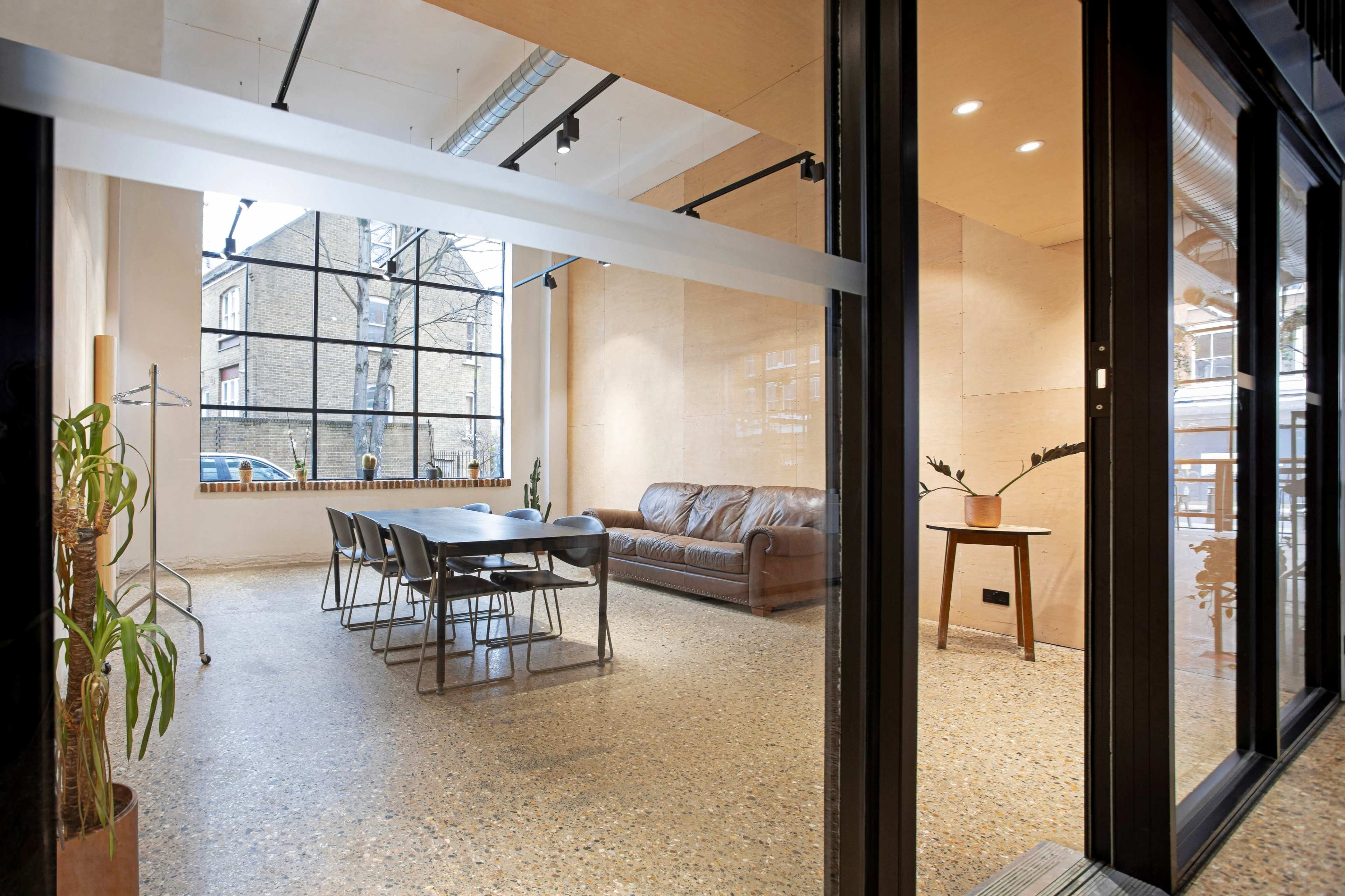 A modern, well-lit meeting space featuring a long table, chairs, a sofa, and large windows.