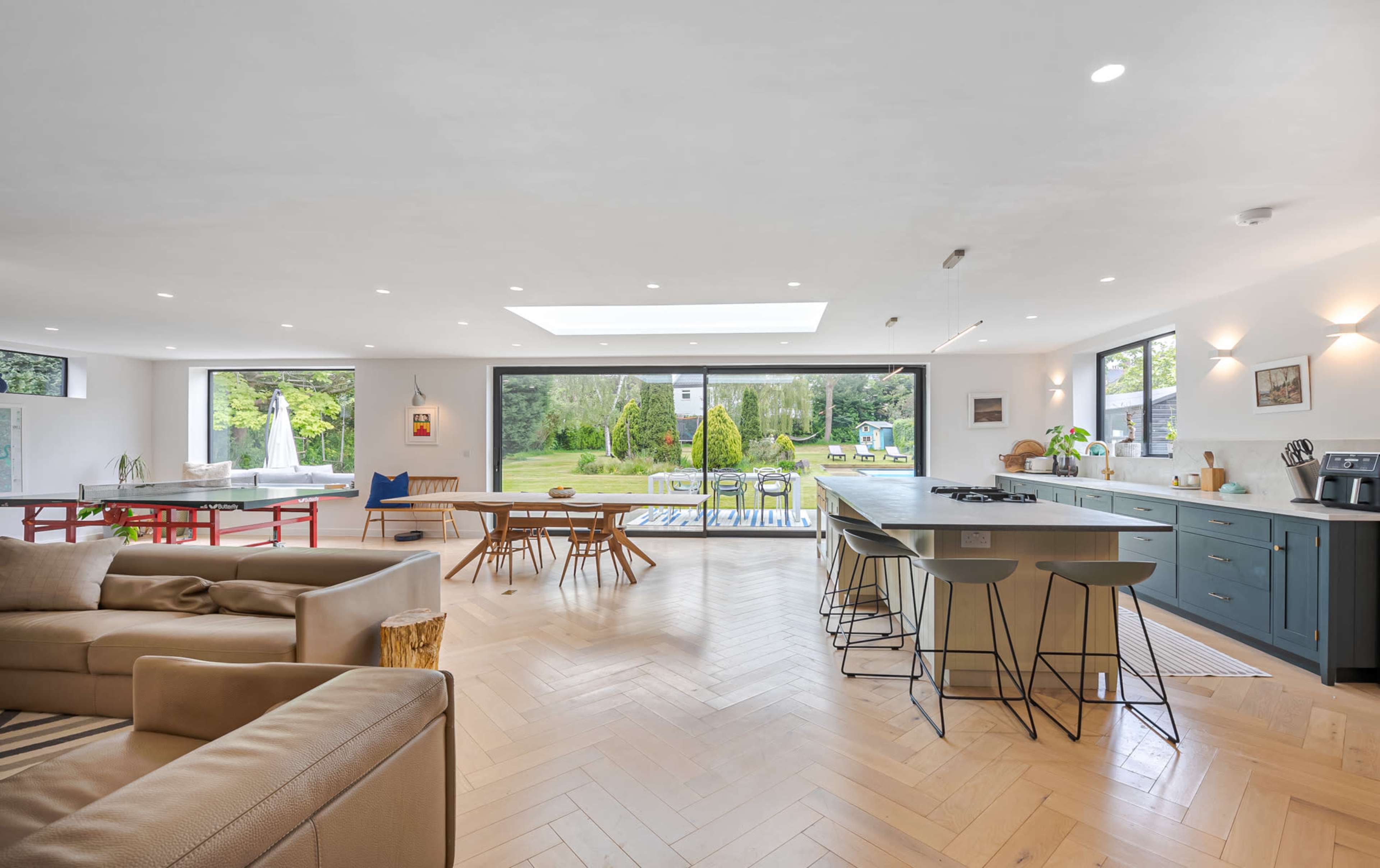 A spacious, open-plan kitchen and living area with large windows overlooking a garden.