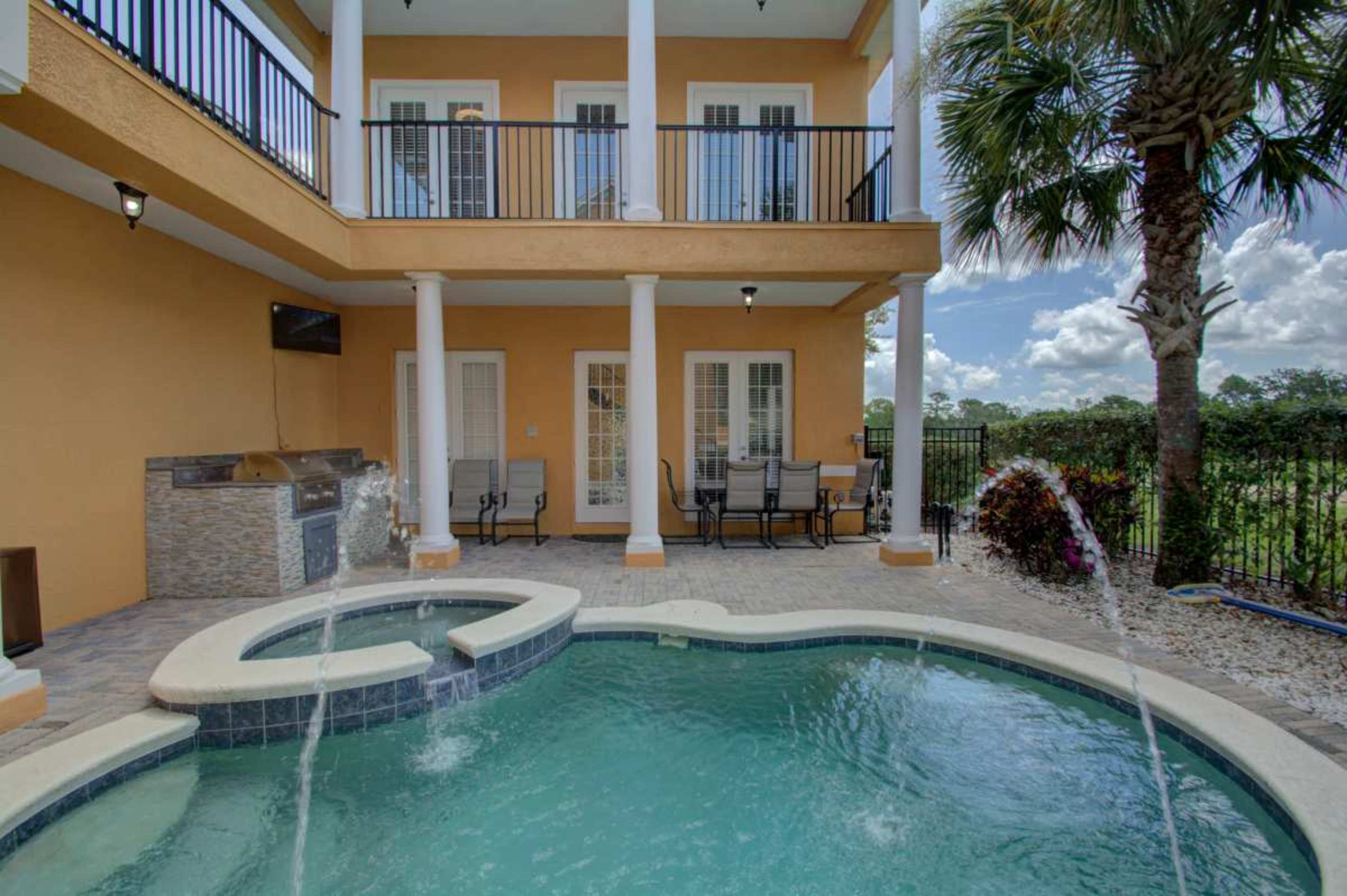 The image shows a two-story house with an outdoor pool and spa area, surrounded by a wrought iron fence and palm trees.