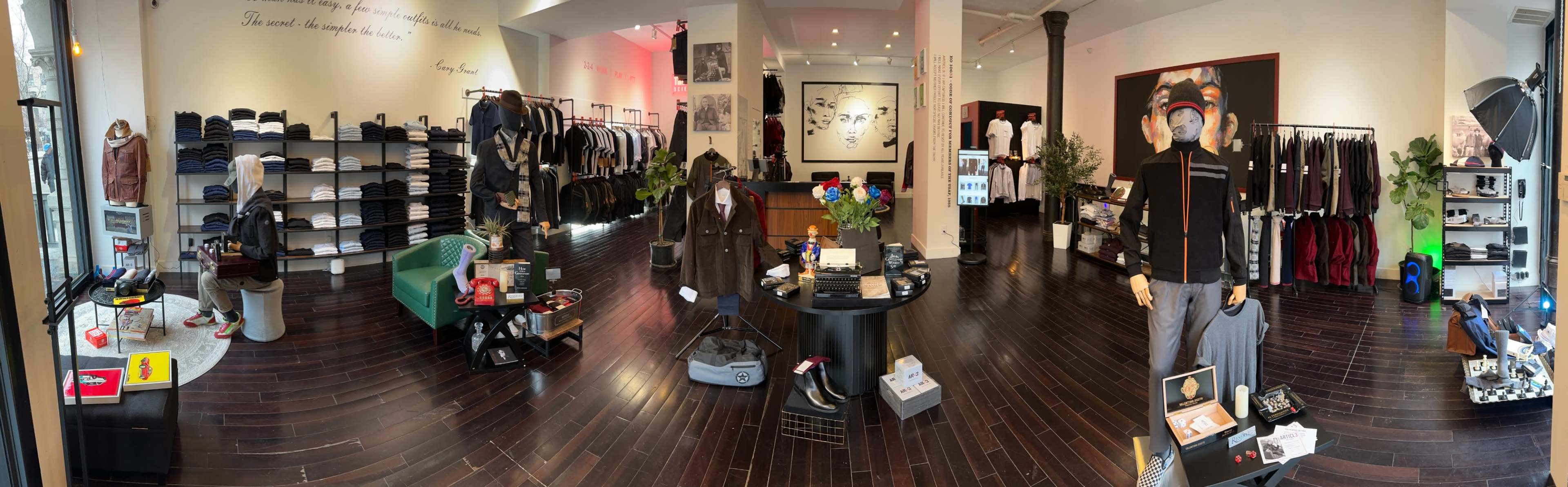 The image shows a clothing store interior with displays of apparel, accessories, and seating arrangements in an organized layout.