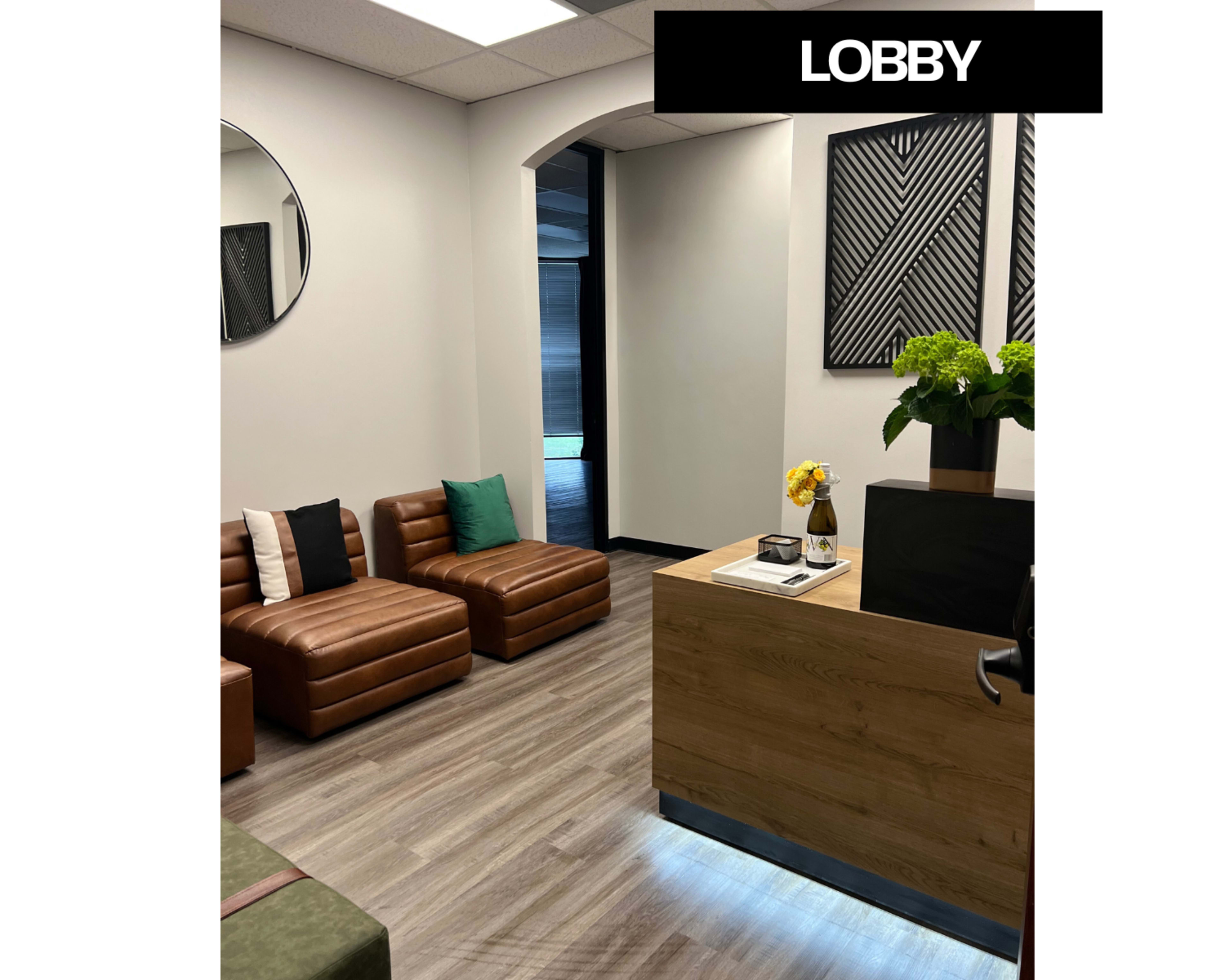 The lobby features modern seating with leather couches, a reception desk, and decor including flower arrangements and wall art.