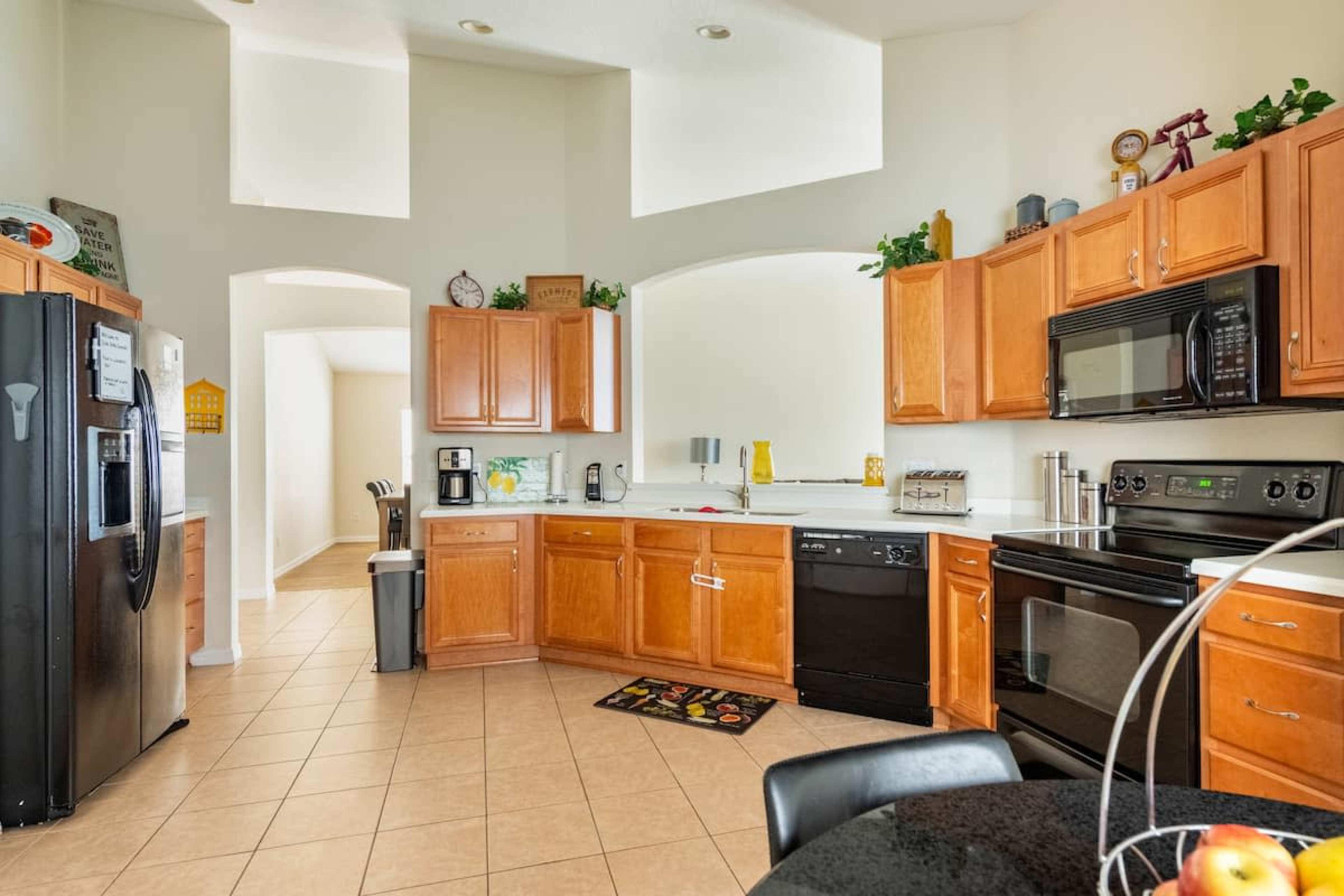 A spacious kitchen features wooden cabinets, black appliances, and a tiled floor.