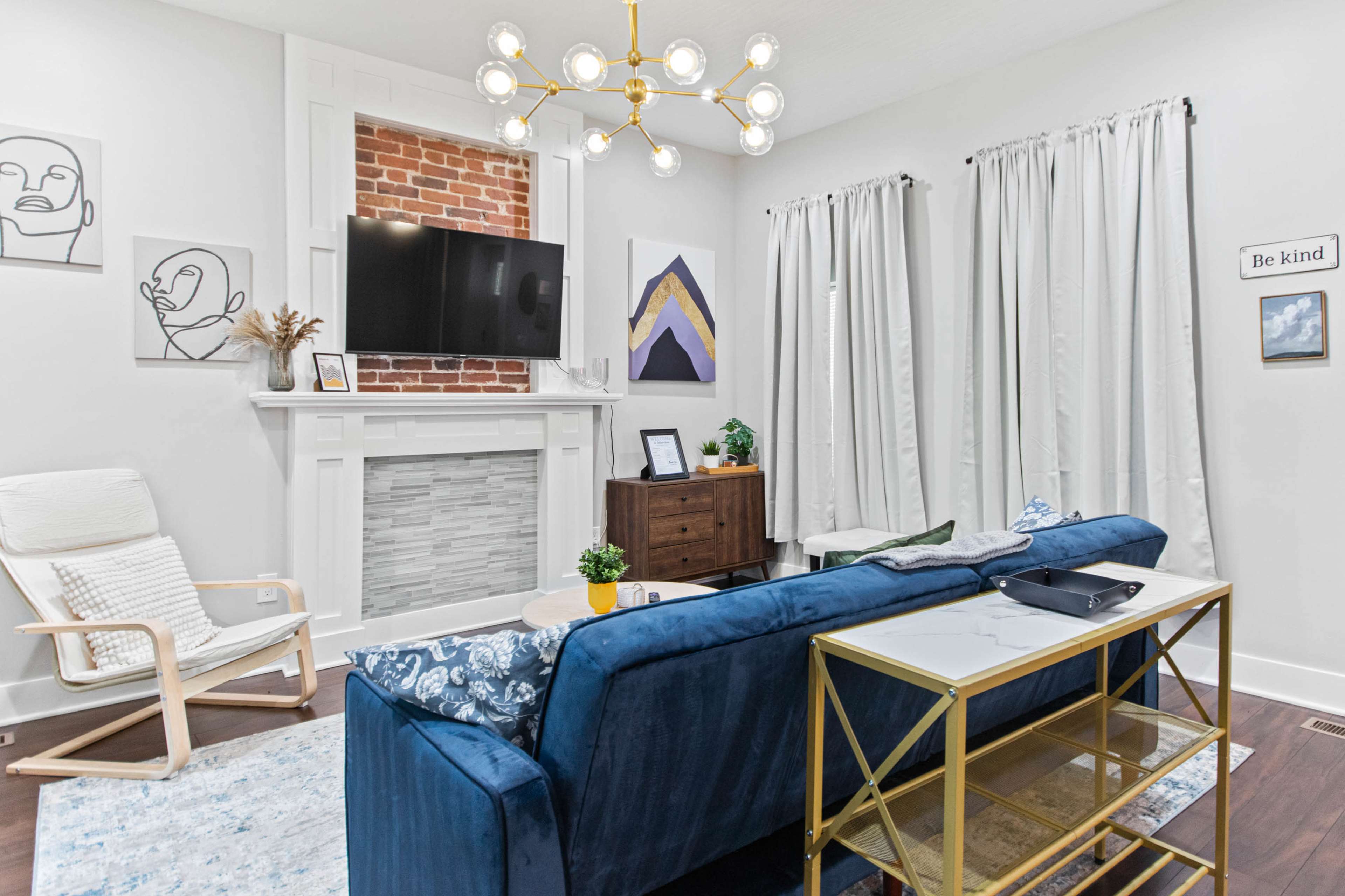 A modern living room features a navy blue couch, a coffee table, and a decorative fireplace with a mounted television above it.