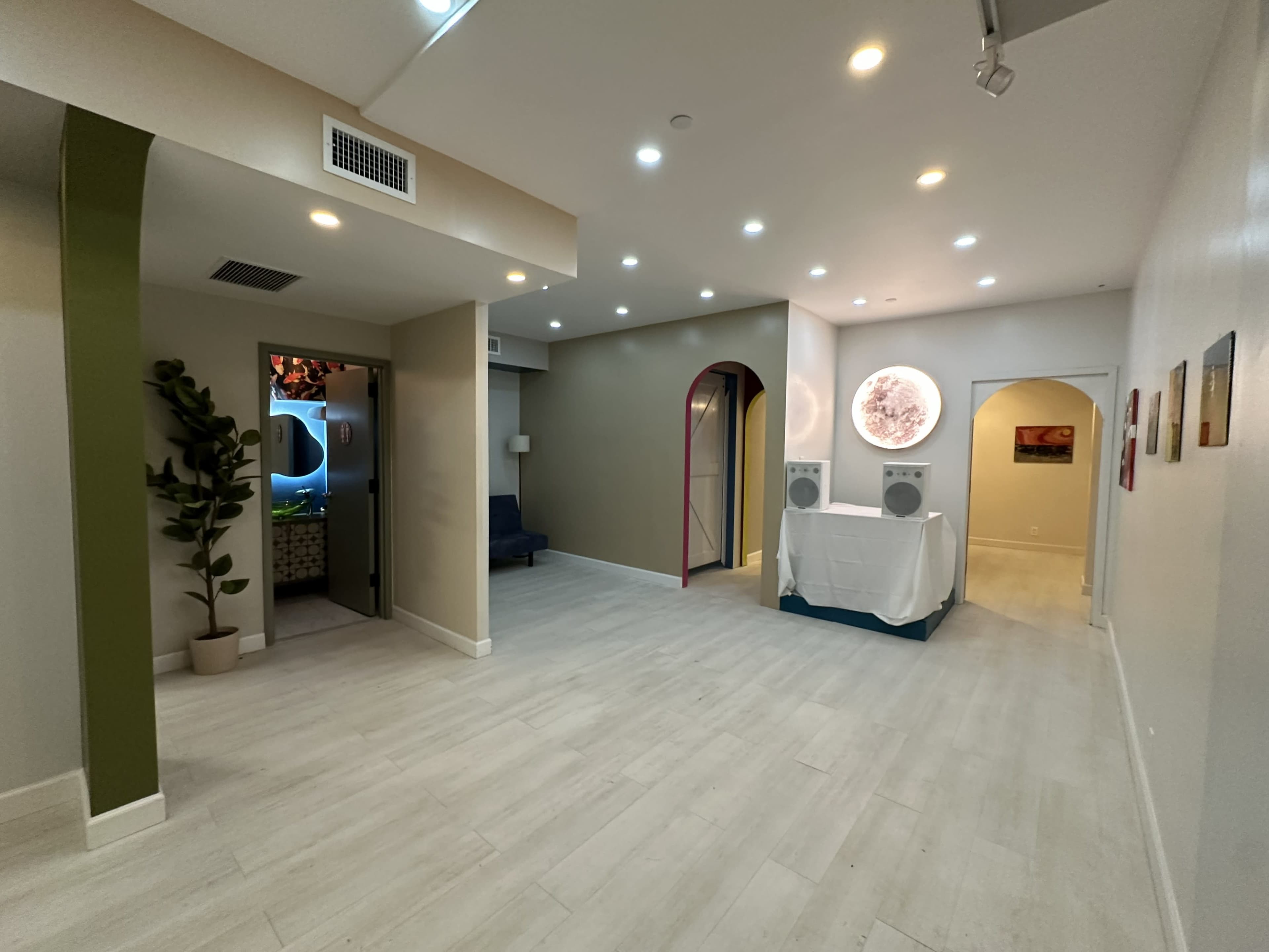 The image shows a well-lit interior space featuring a hallway with several doorways, a reception area with audio equipment, and decorative wall art.