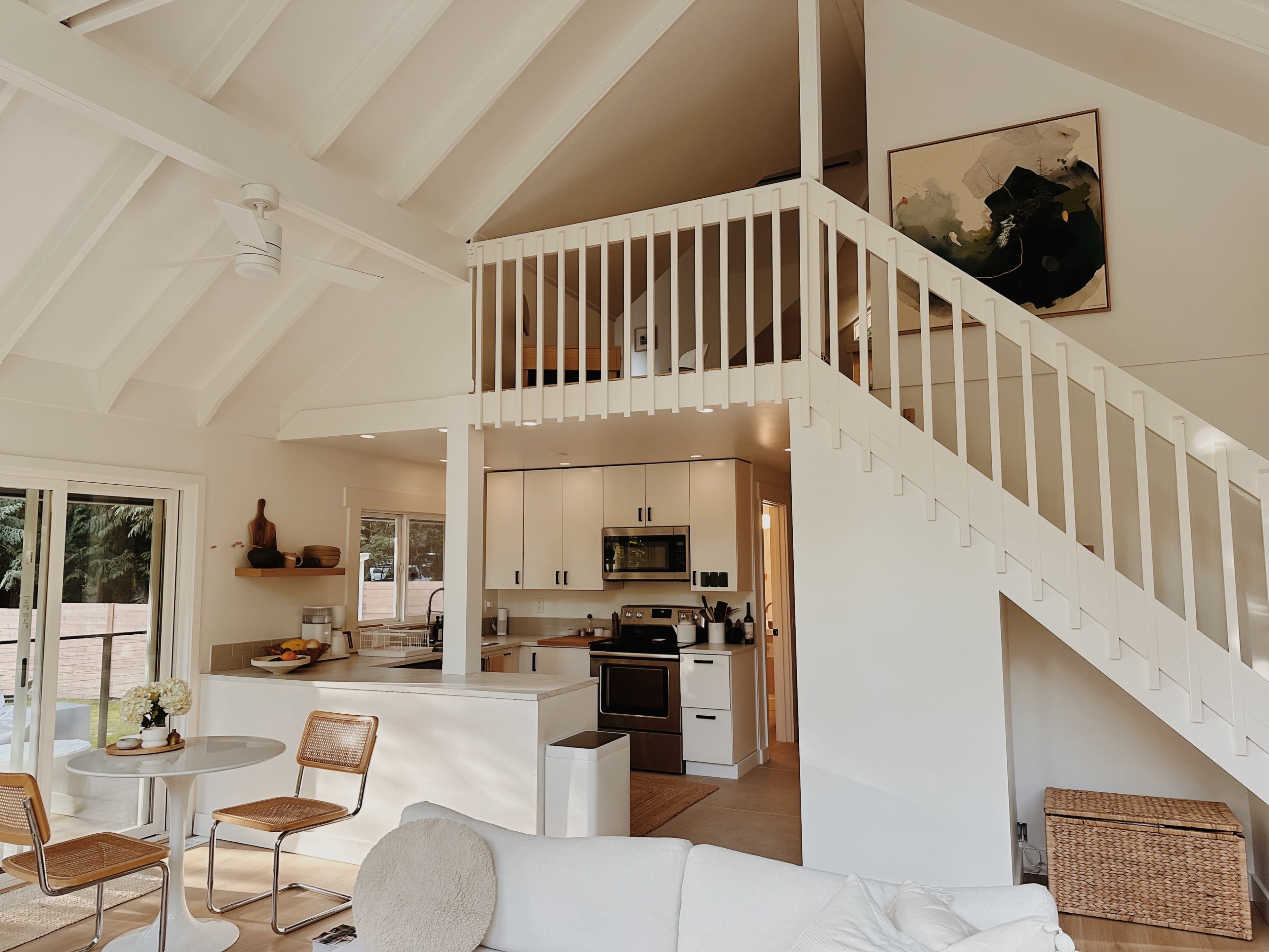 A modern, open-concept living space with a kitchen, dining area, and a staircase leading to a loft.