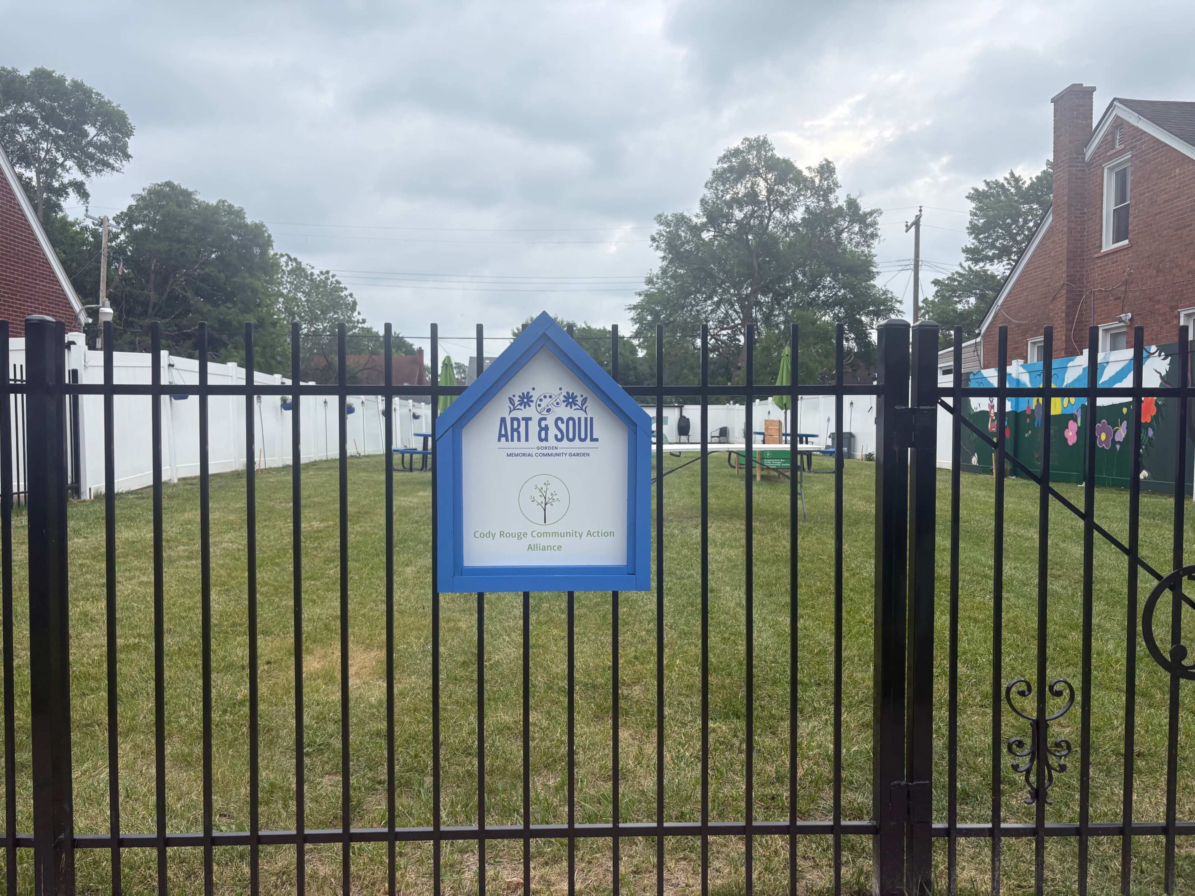 The image shows a fenced outdoor space with a sign that reads "ART & SOUL" at the entrance, surrounded by grassy land and white walls.