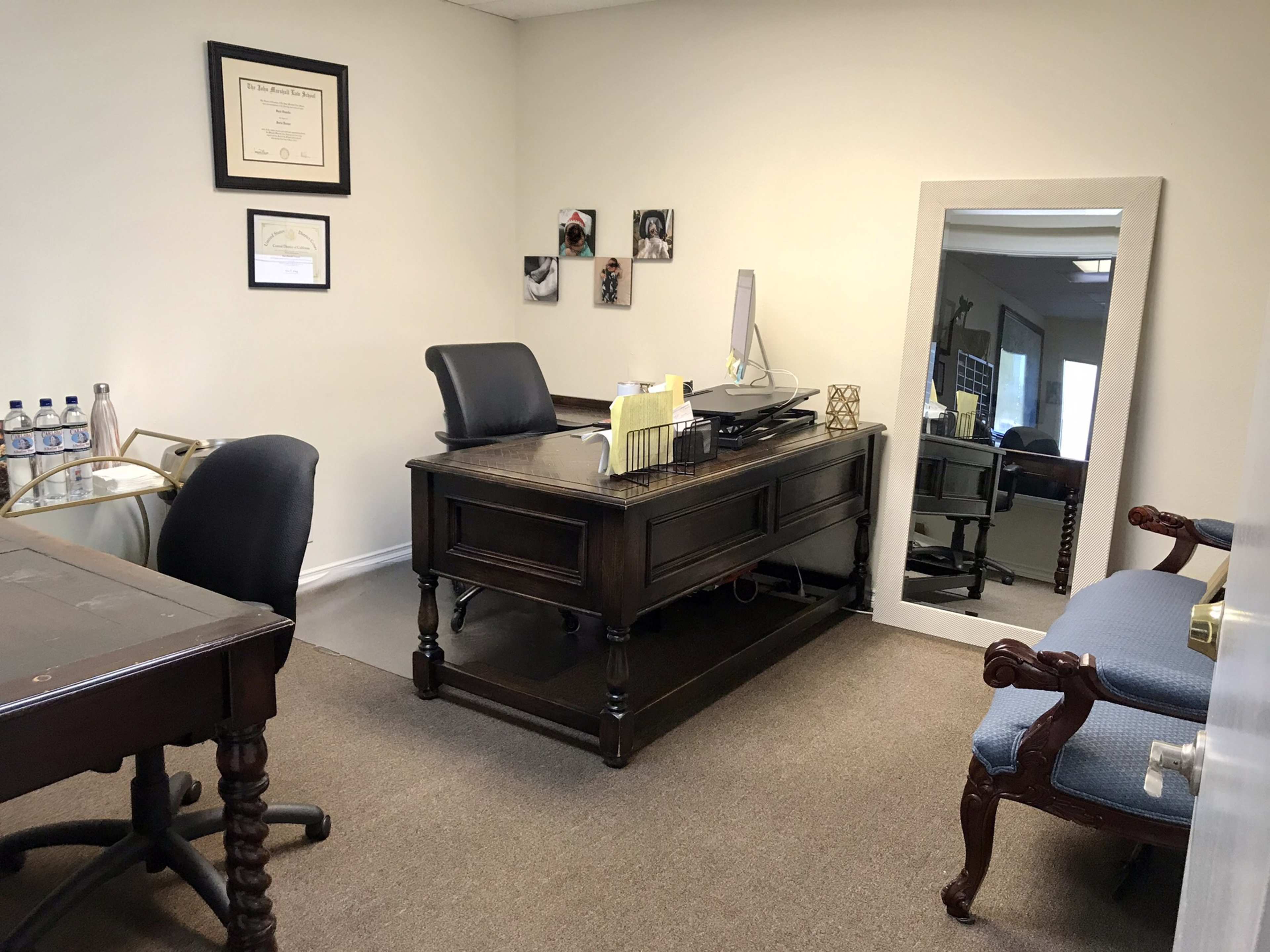 The office features a wooden desk with a computer, a chair, a bench, and a large mirror on the wall.