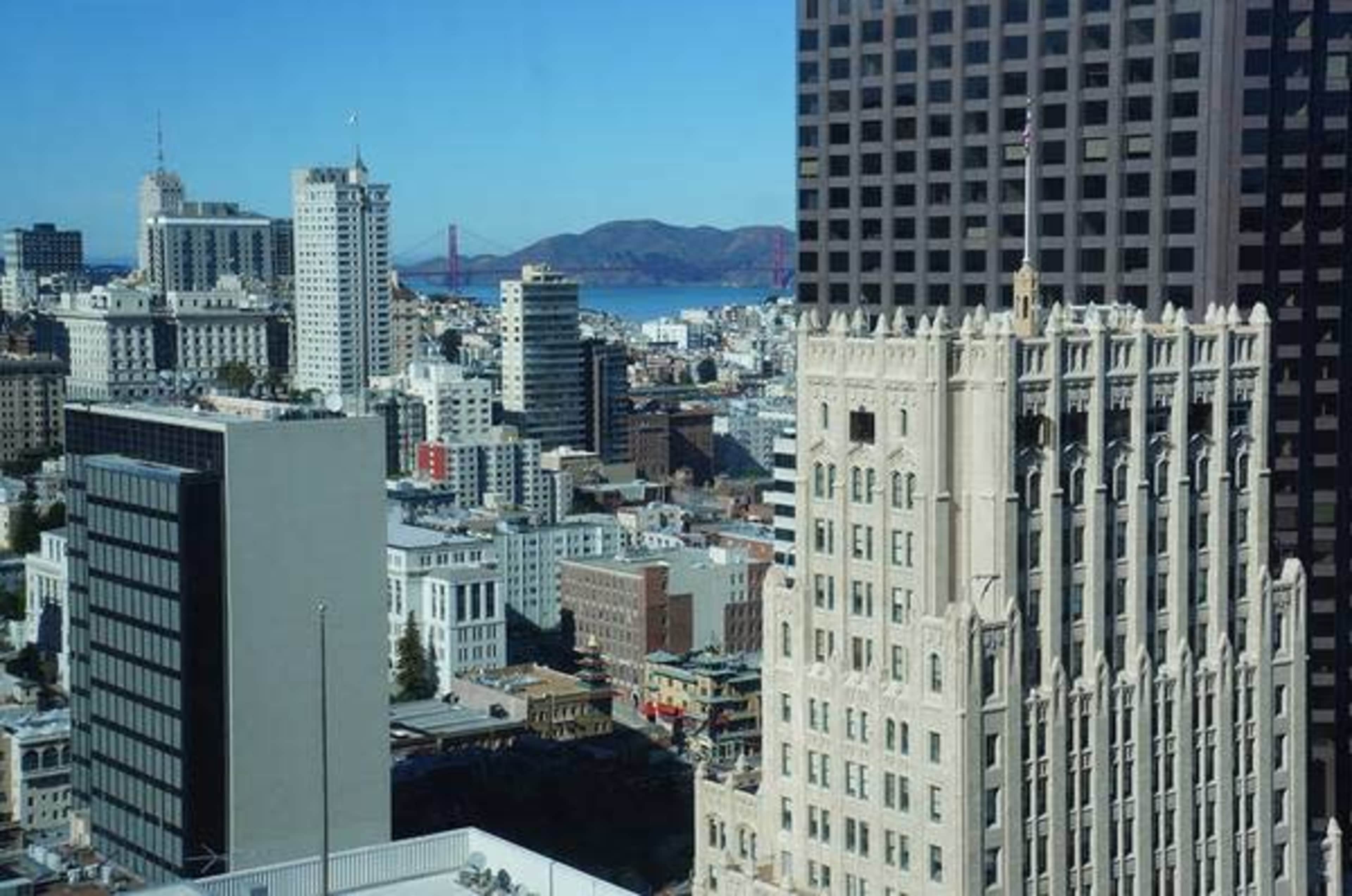 The scene showcases a city skyline of San Francisco featuring a mix of modern and historic buildings with the Golden Gate Bridge visible in the background.