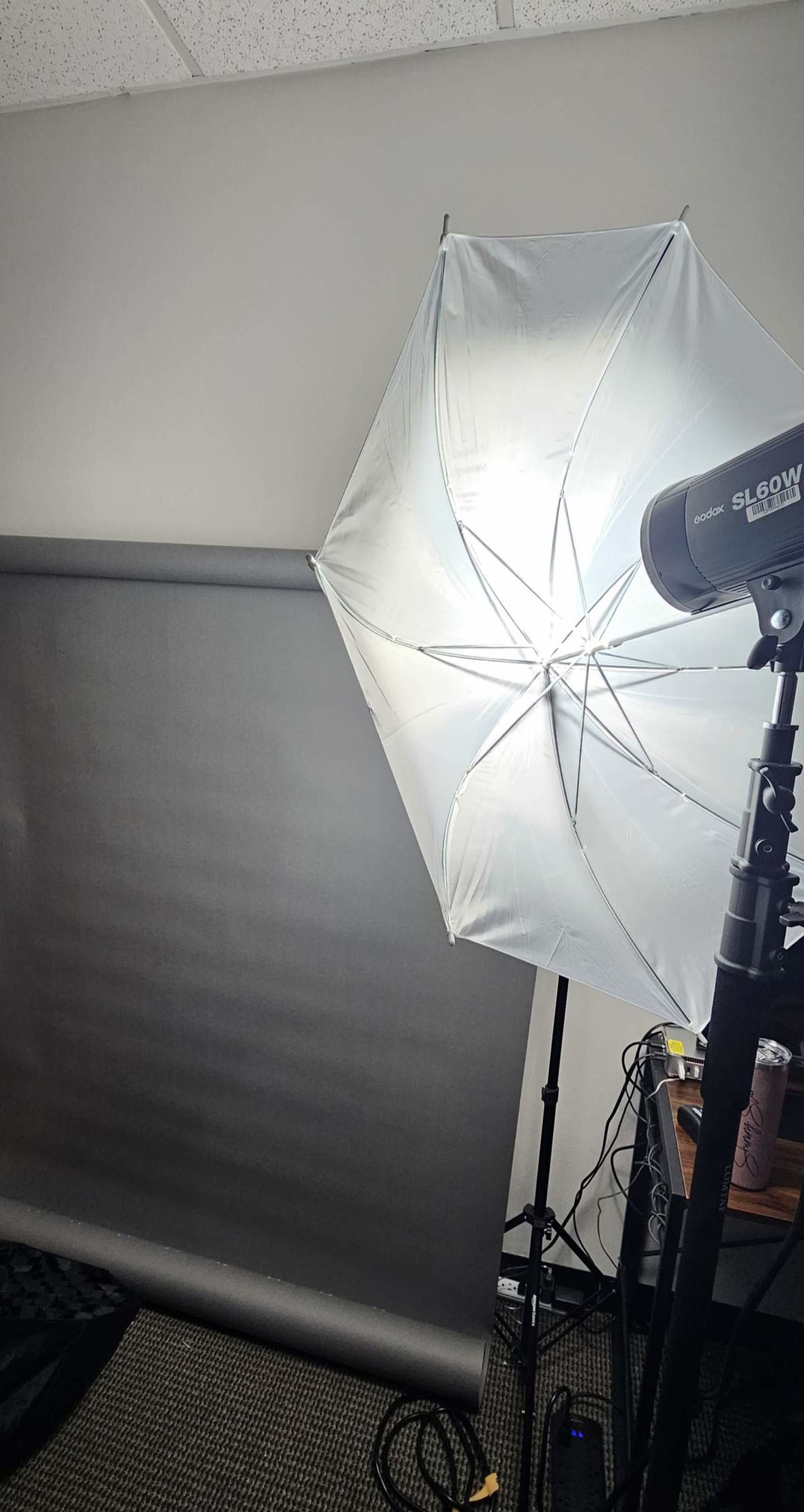 A photography setup with a softbox light and a gray backdrop on a stand in an indoor setting.