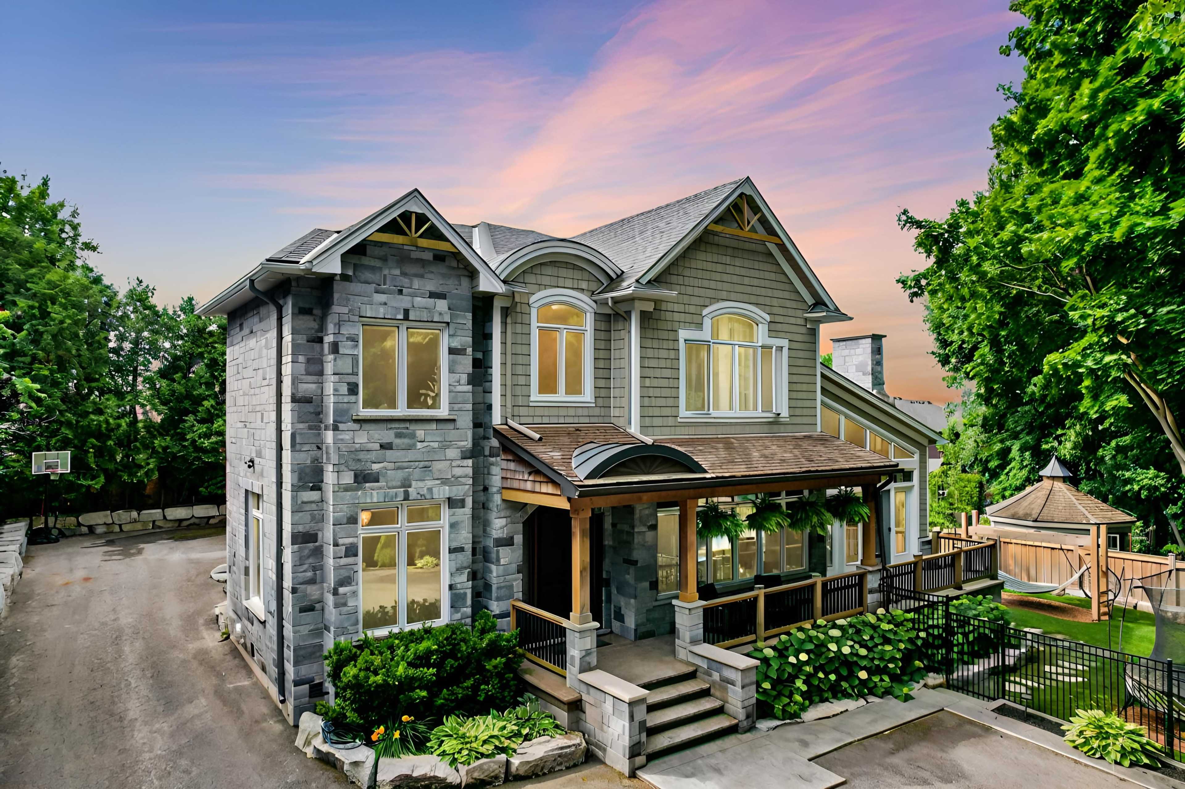 A large two-story house with stone and wood siding features a front porch and well-maintained landscaping.