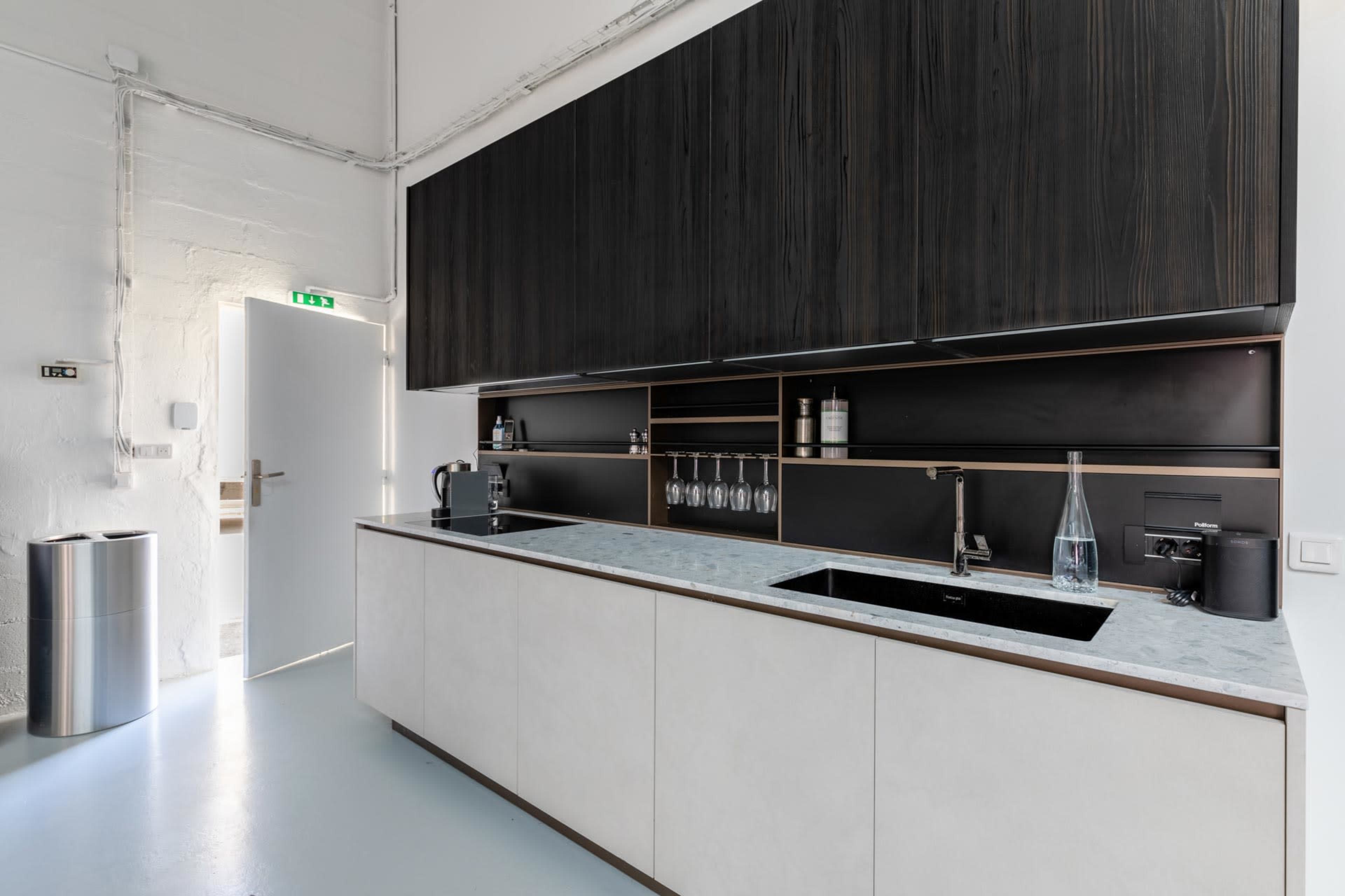 A modern kitchen features a minimalist design with sleek cabinetry, a marble countertop, and a double sink.