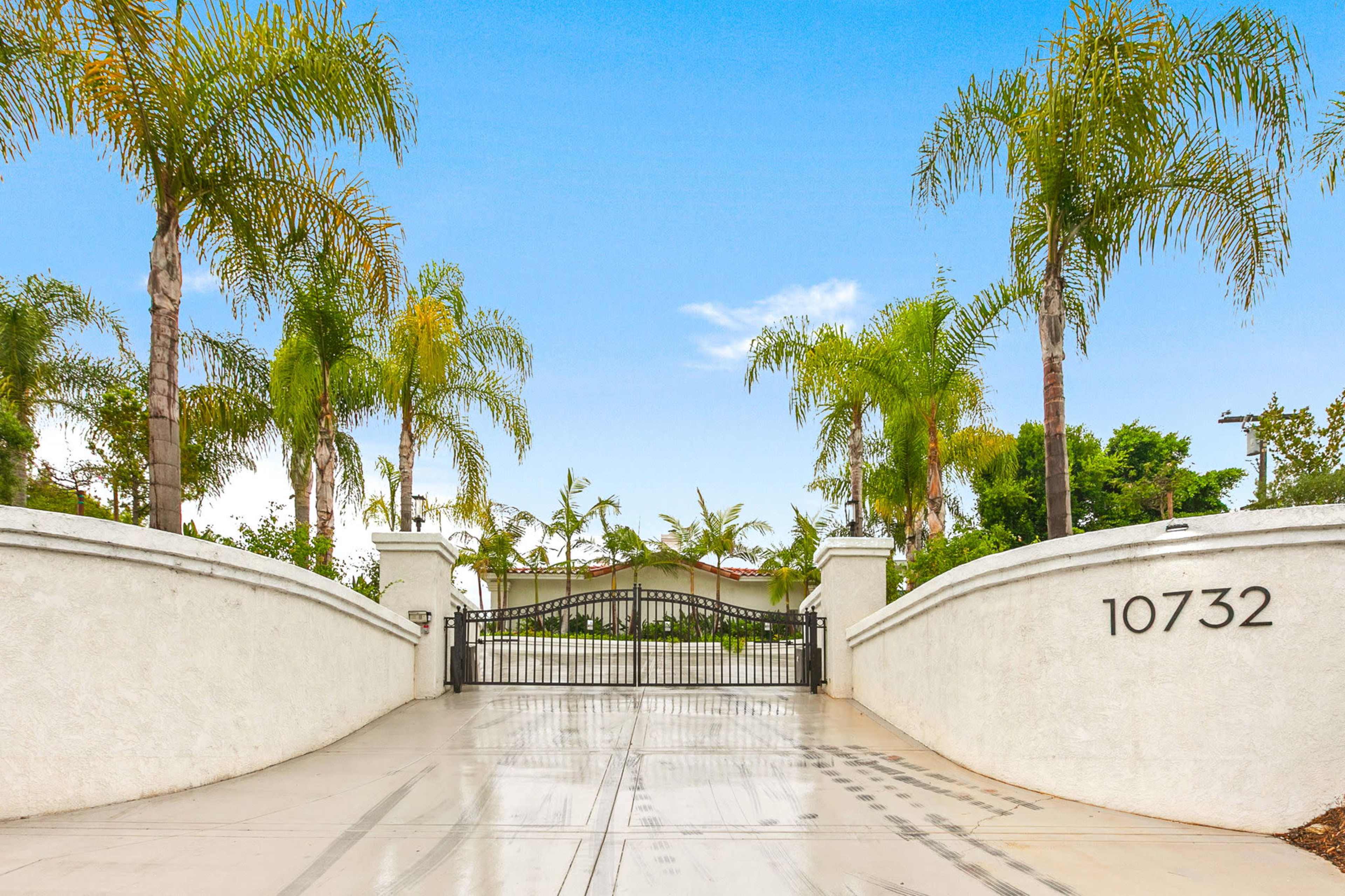 A gated entrance with palm trees leads to a property at 10732.