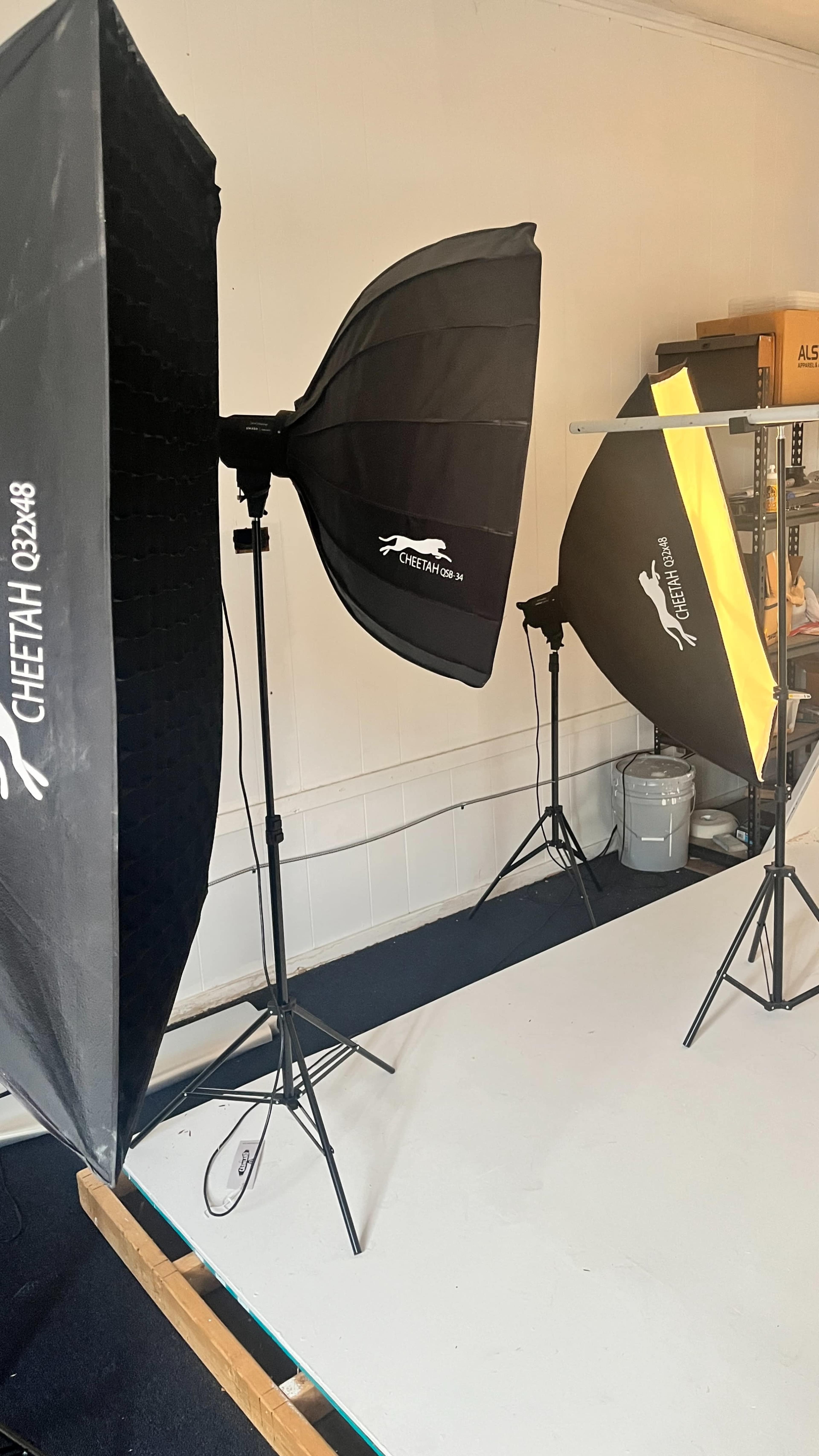 Two softbox light setups on stands in a photography studio, positioned on a white backdrop.