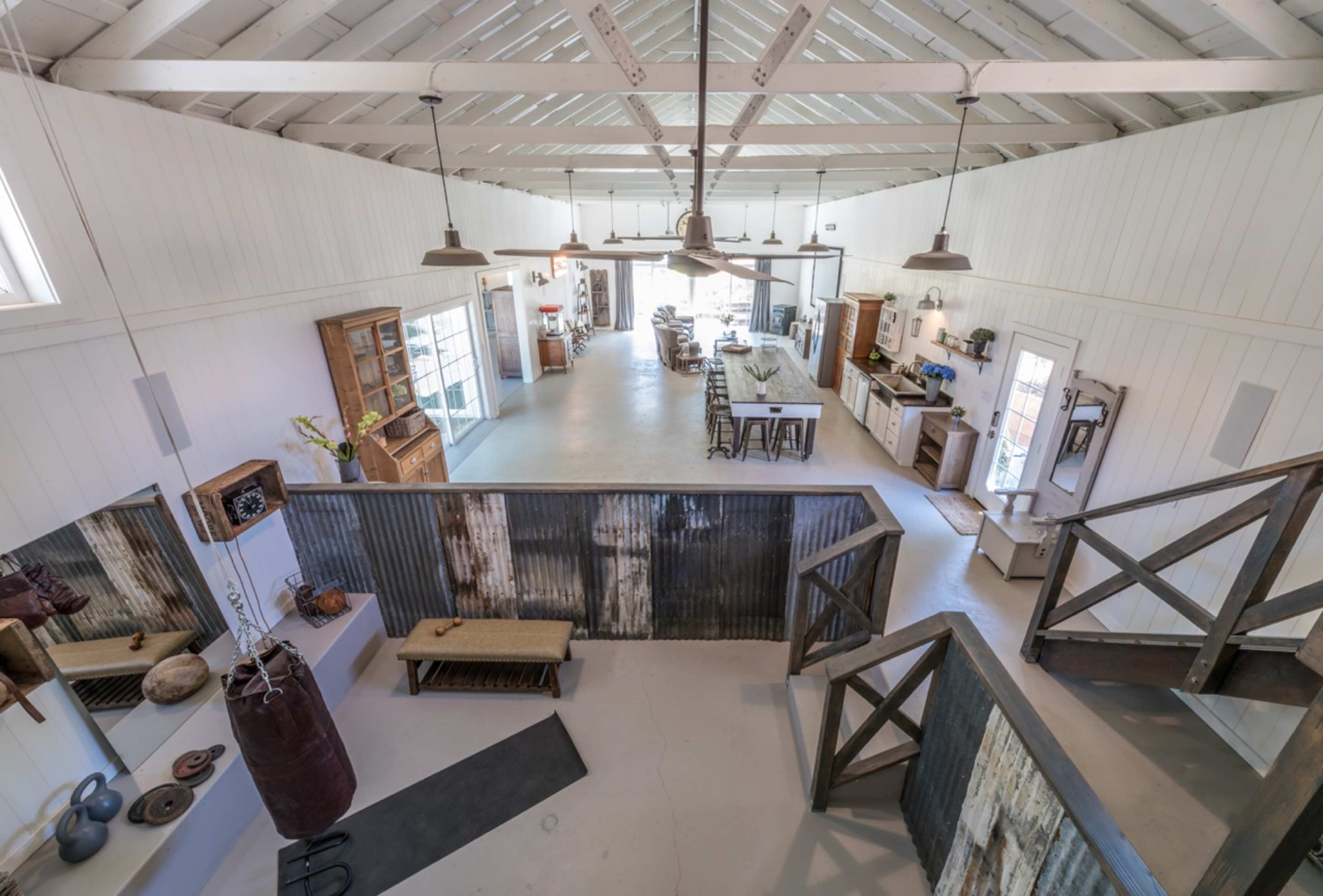 A spacious, open-concept interior of a barn-style building featuring a kitchen, dining area, and living space with industrial design elements.