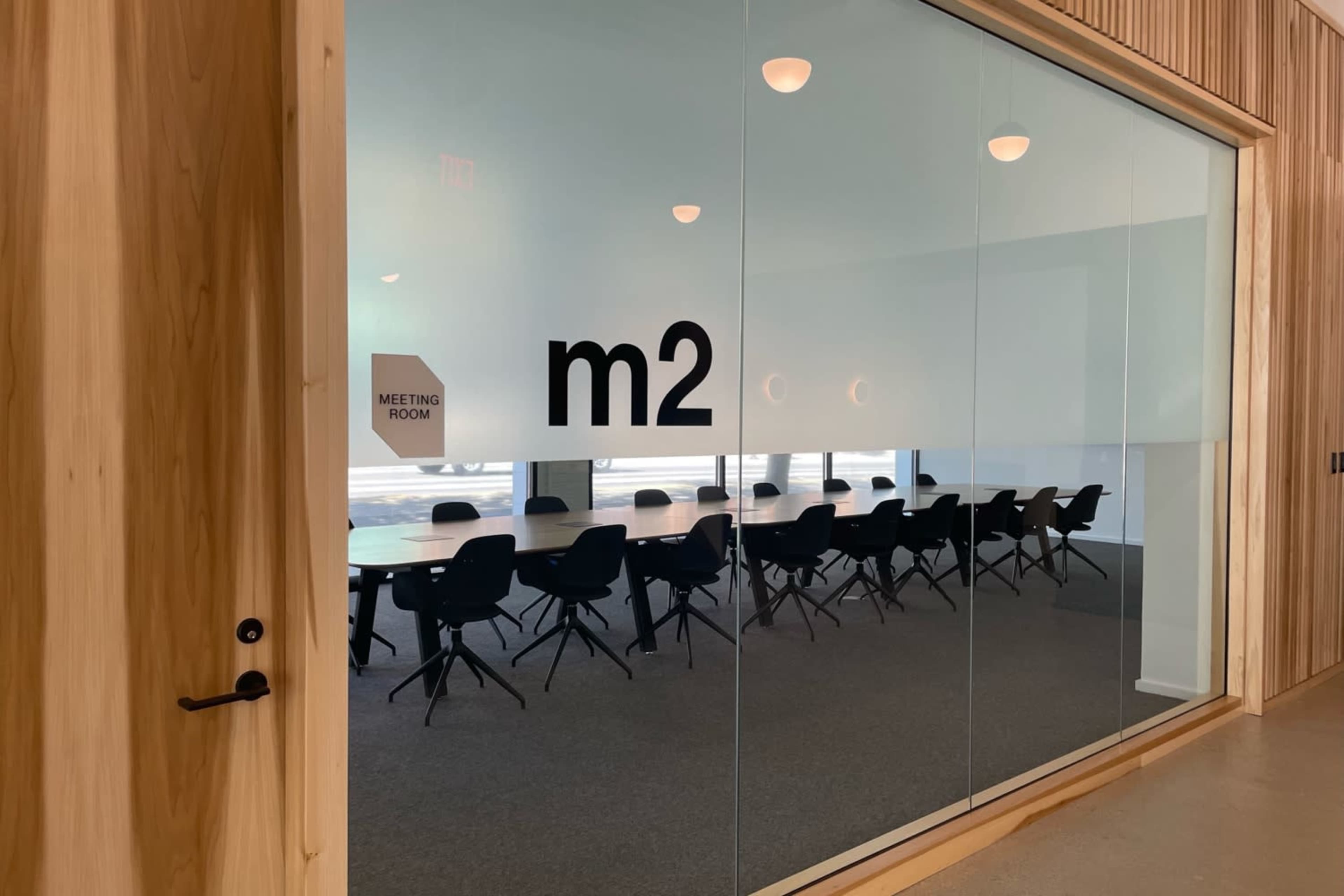 A meeting room labeled "m2" is visible through a glass wall, featuring a long table surrounded by black chairs.