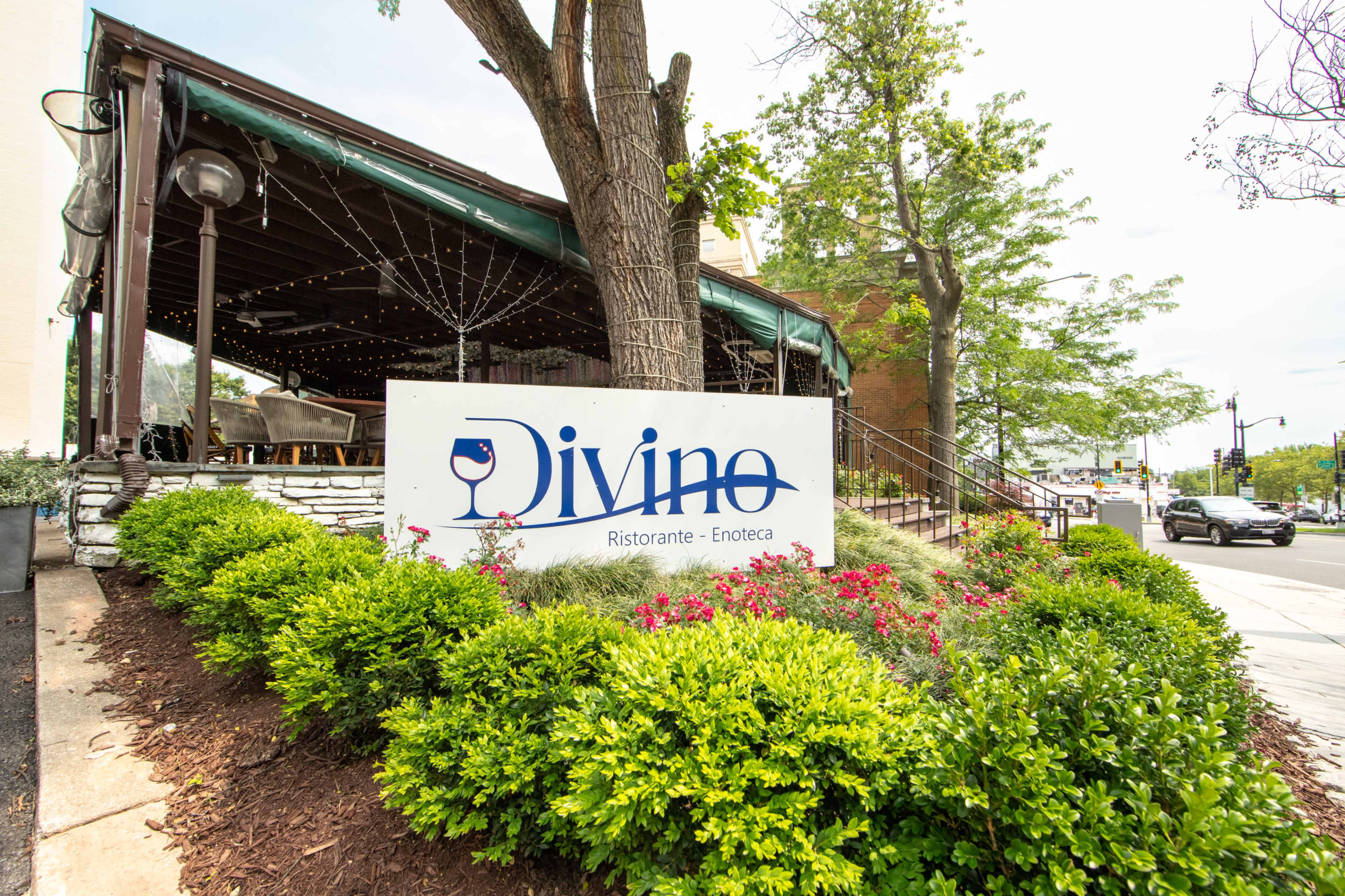 The image shows a restaurant named "Divino Ristorante - Enoteca," with a landscaped area featuring shrubs and flowers in front of the establishment.