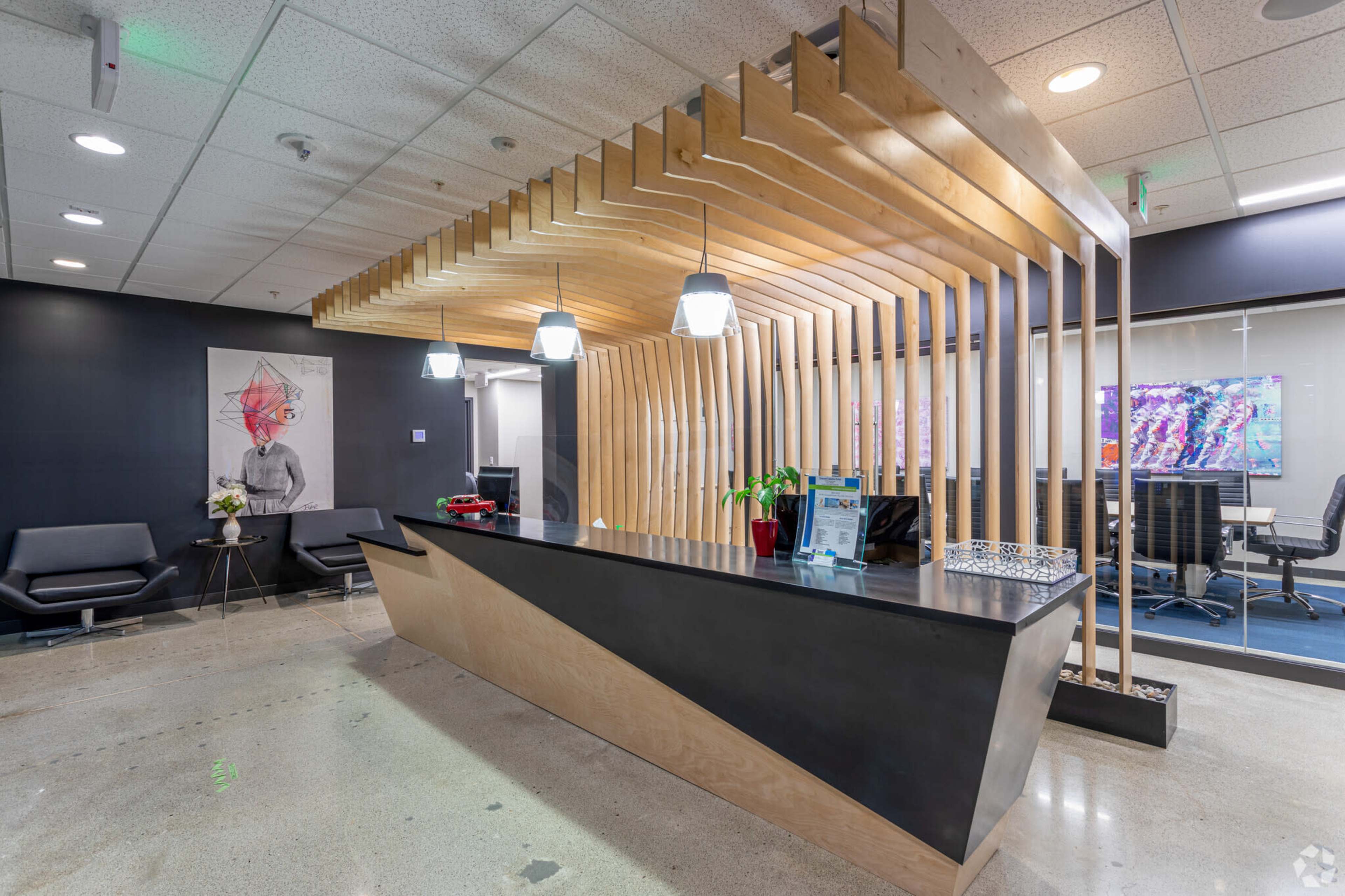 A modern reception area featuring a sleek wooden reception desk, artistic wall decor, and ambient lighting.