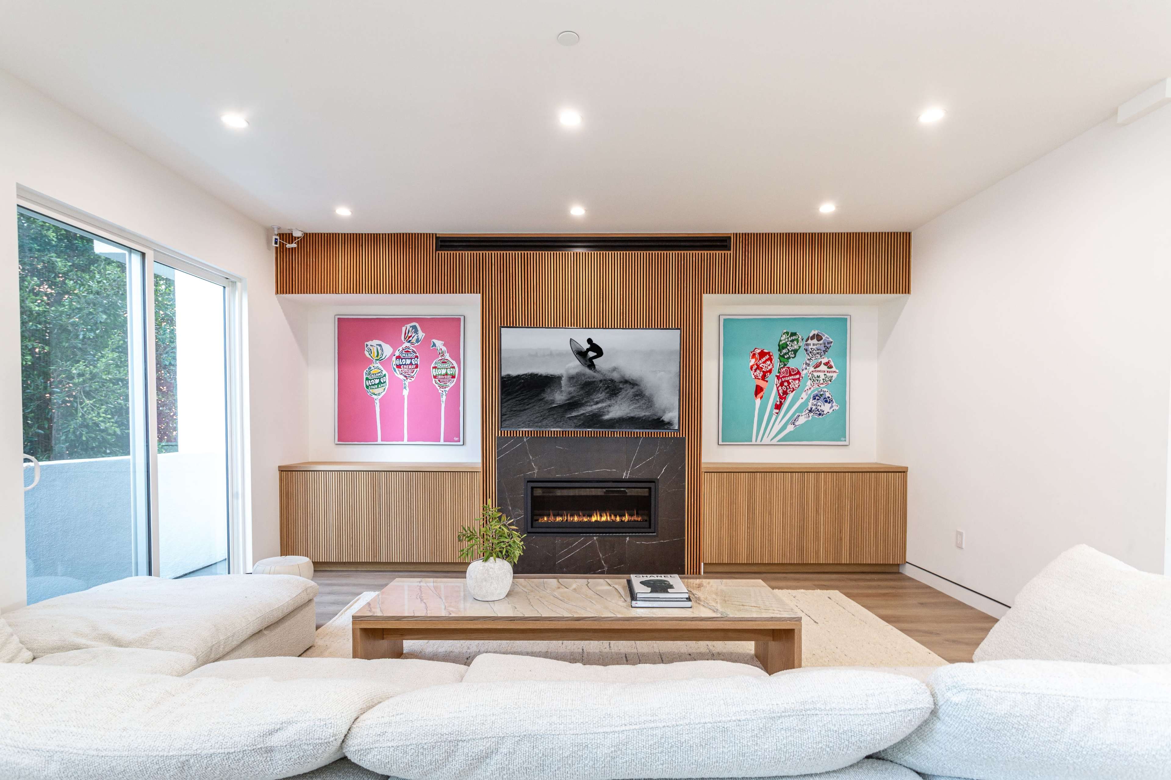 A modern living room features a sectional sofa, a fireplace, and colorful artwork on the walls.