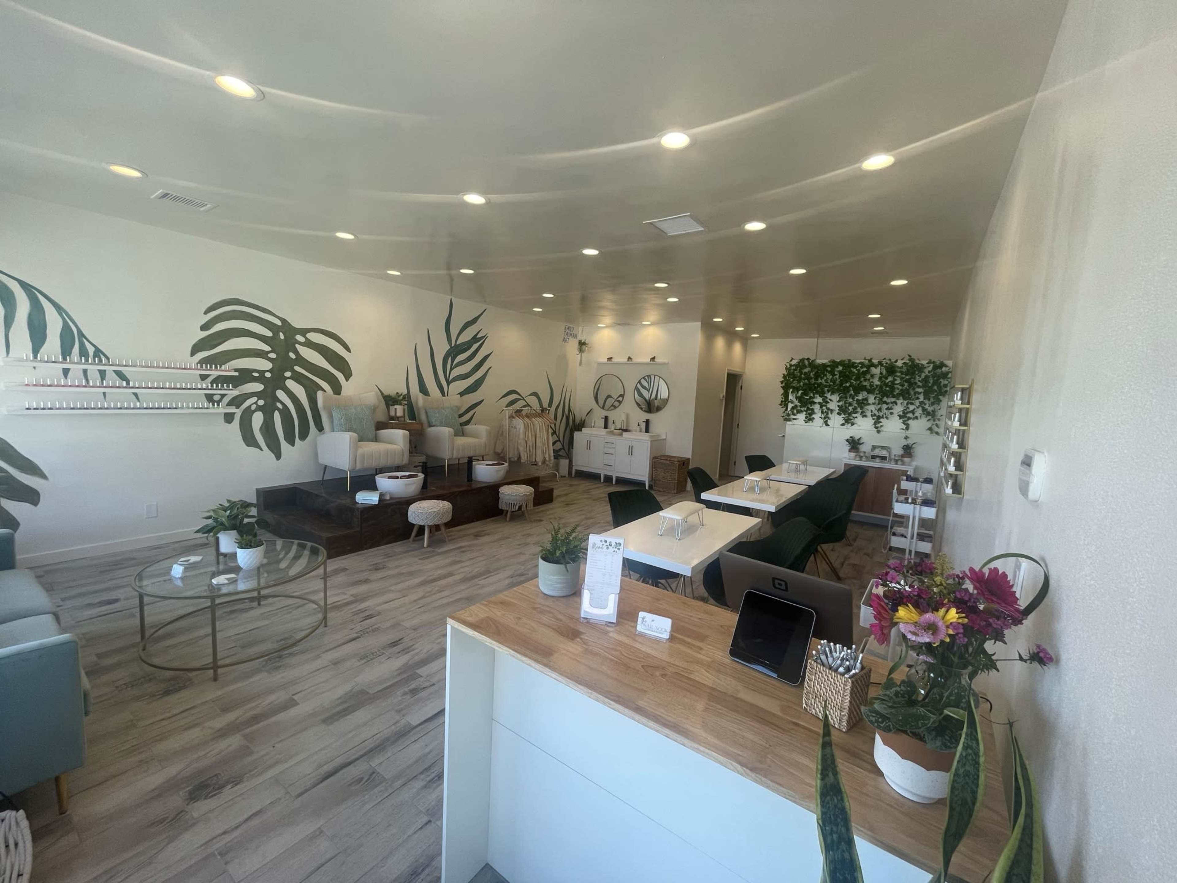 A modern spa interior with comfortable seating, plants on the walls, and a reception area featuring a wooden counter.