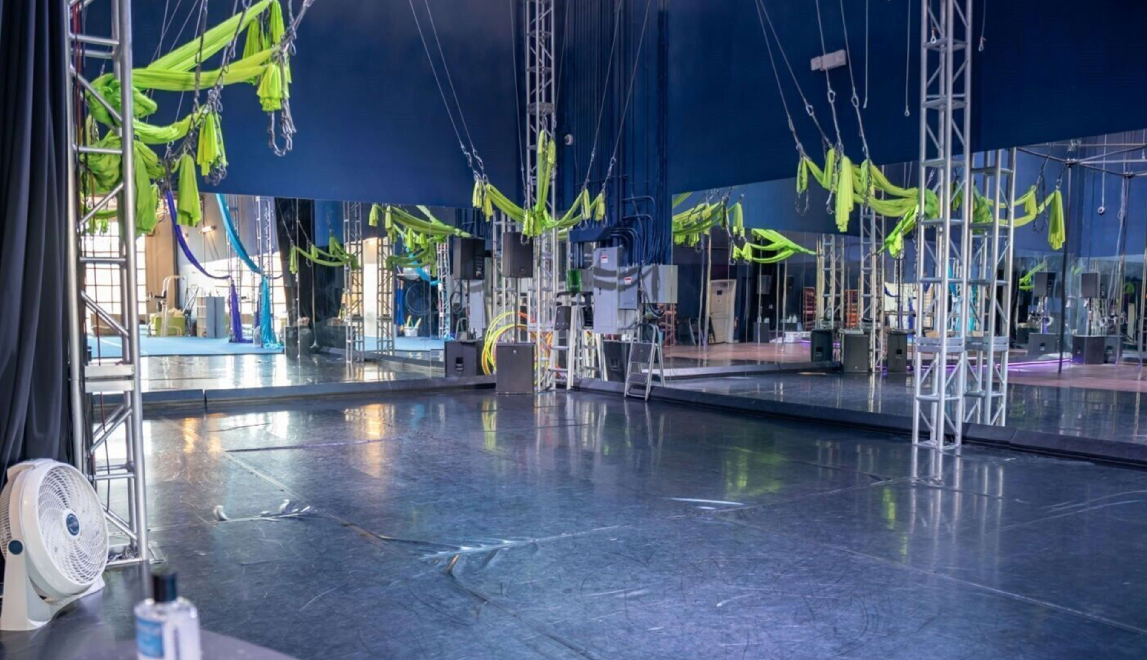 A spacious aerial performance studio with suspended fabric and large mirrors.
