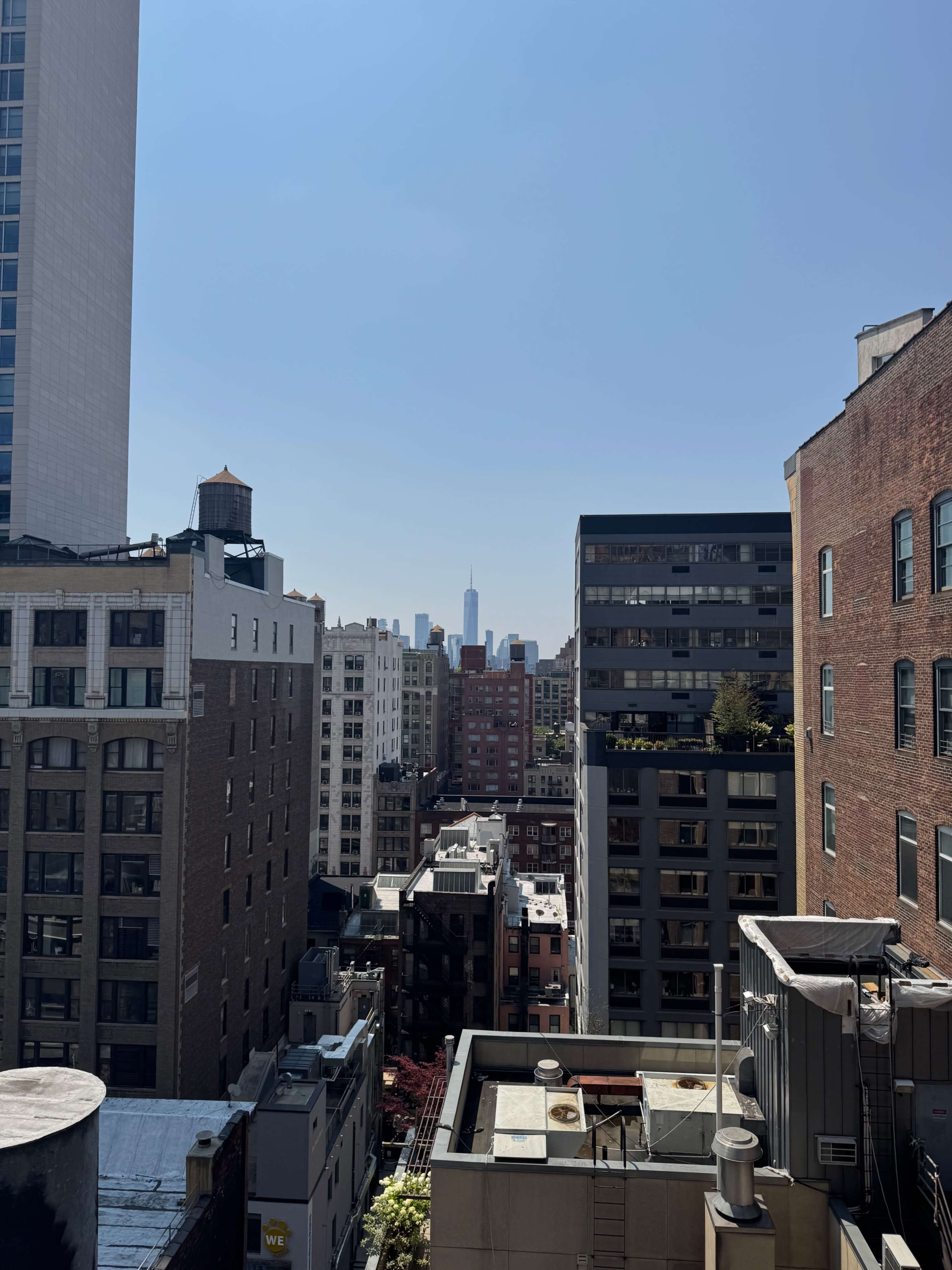 The image shows a view of a cityscape with various buildings, including tall skyscrapers and residential structures, under a clear blue sky.