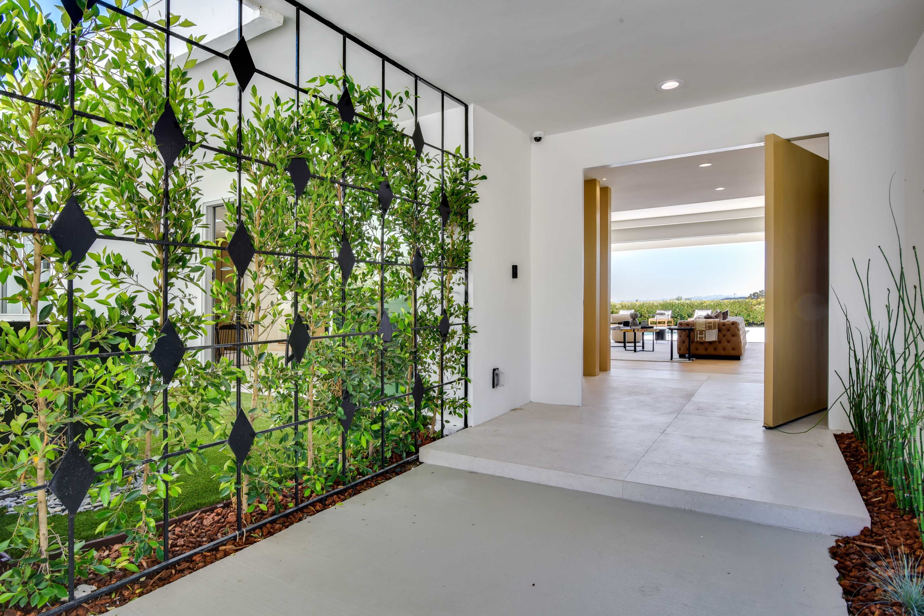 A modern entryway features a decorative green wall and opens up to an outdoor living area.