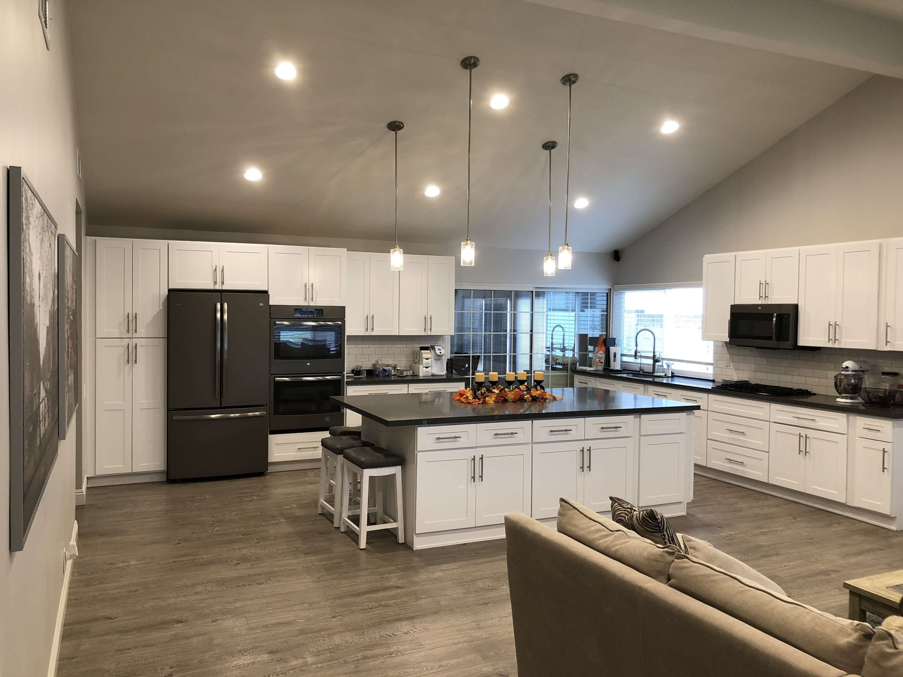 The kitchen features white cabinetry, modern appliances, and a large island with seating.