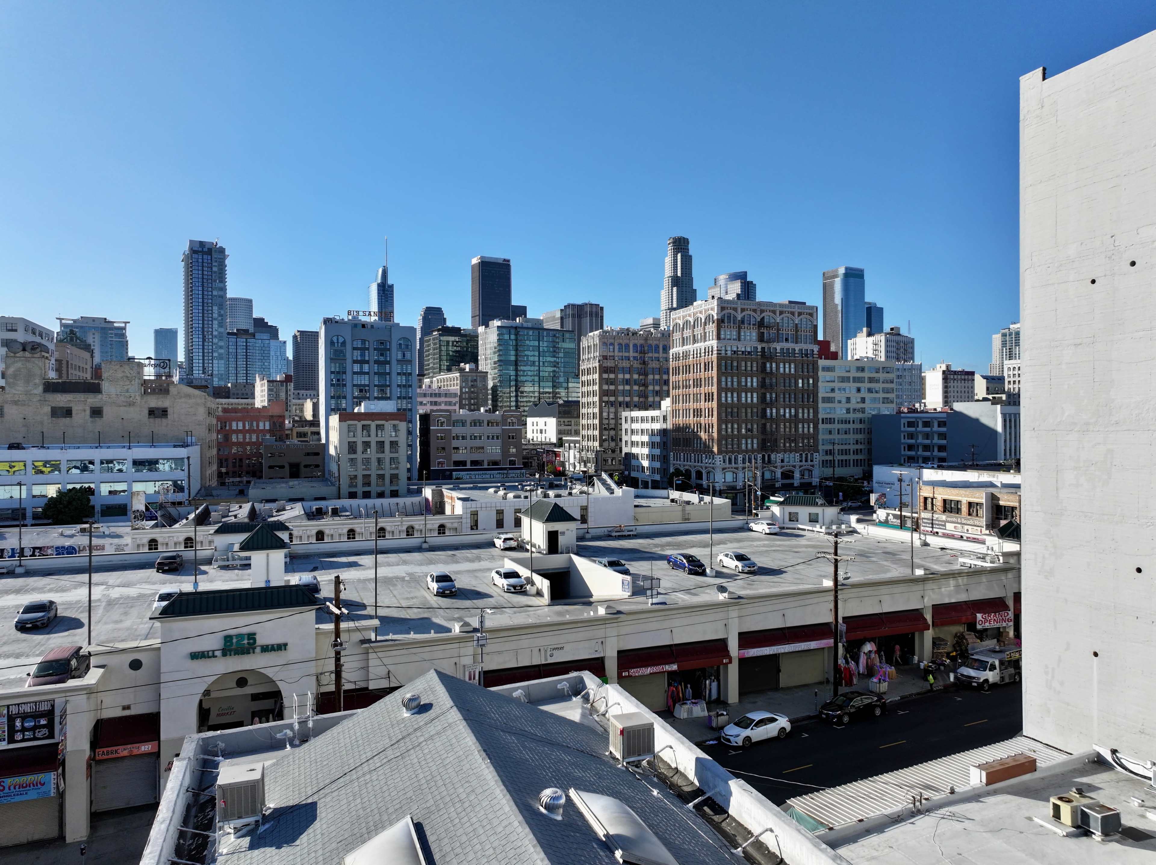 A view of a city skyline with skyscrapers in the background, overlooking rooftops and parking areas in the foreground.