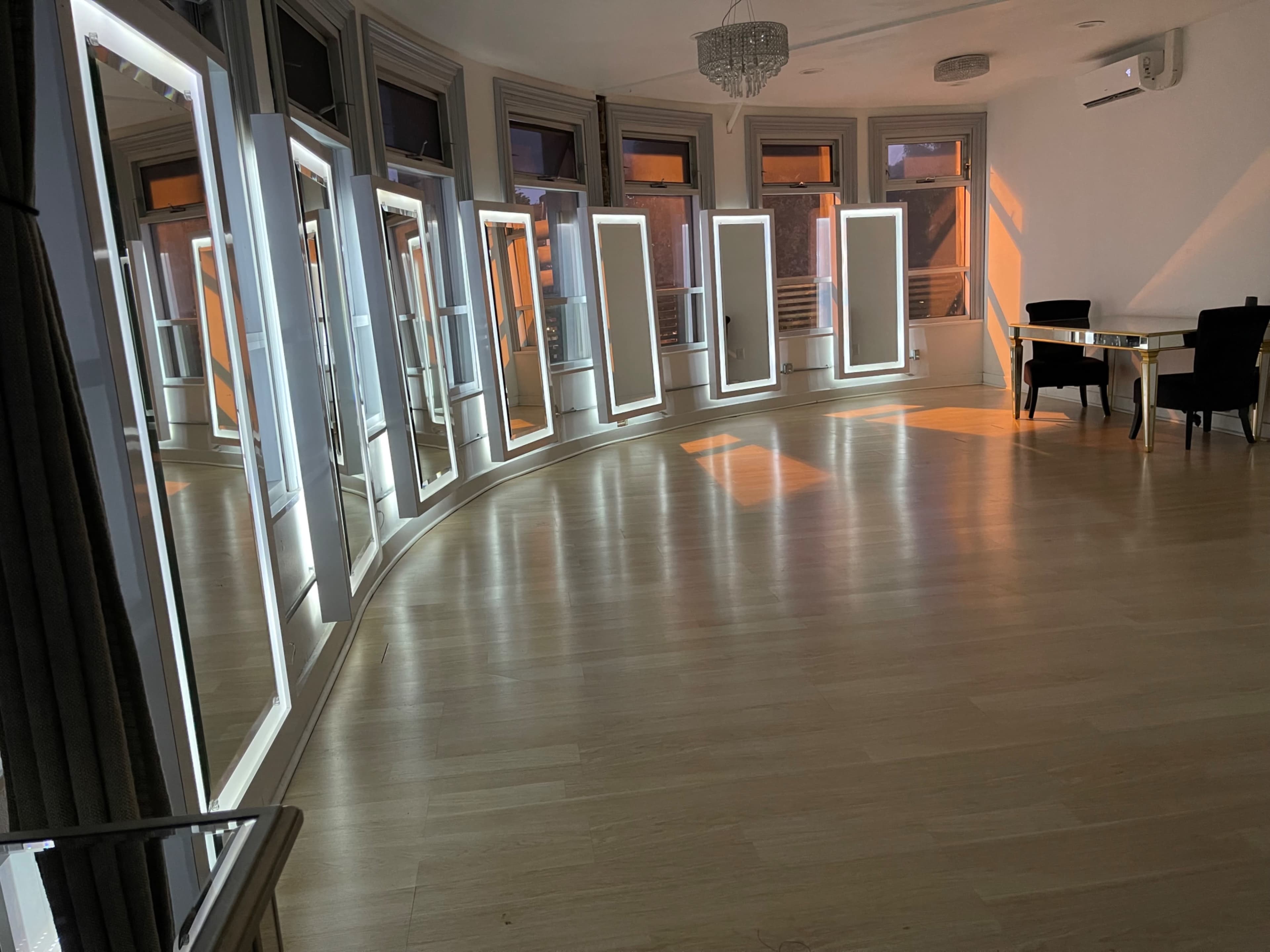 The image shows a curved room with several large mirrors positioned along the walls, reflecting light from the windows.