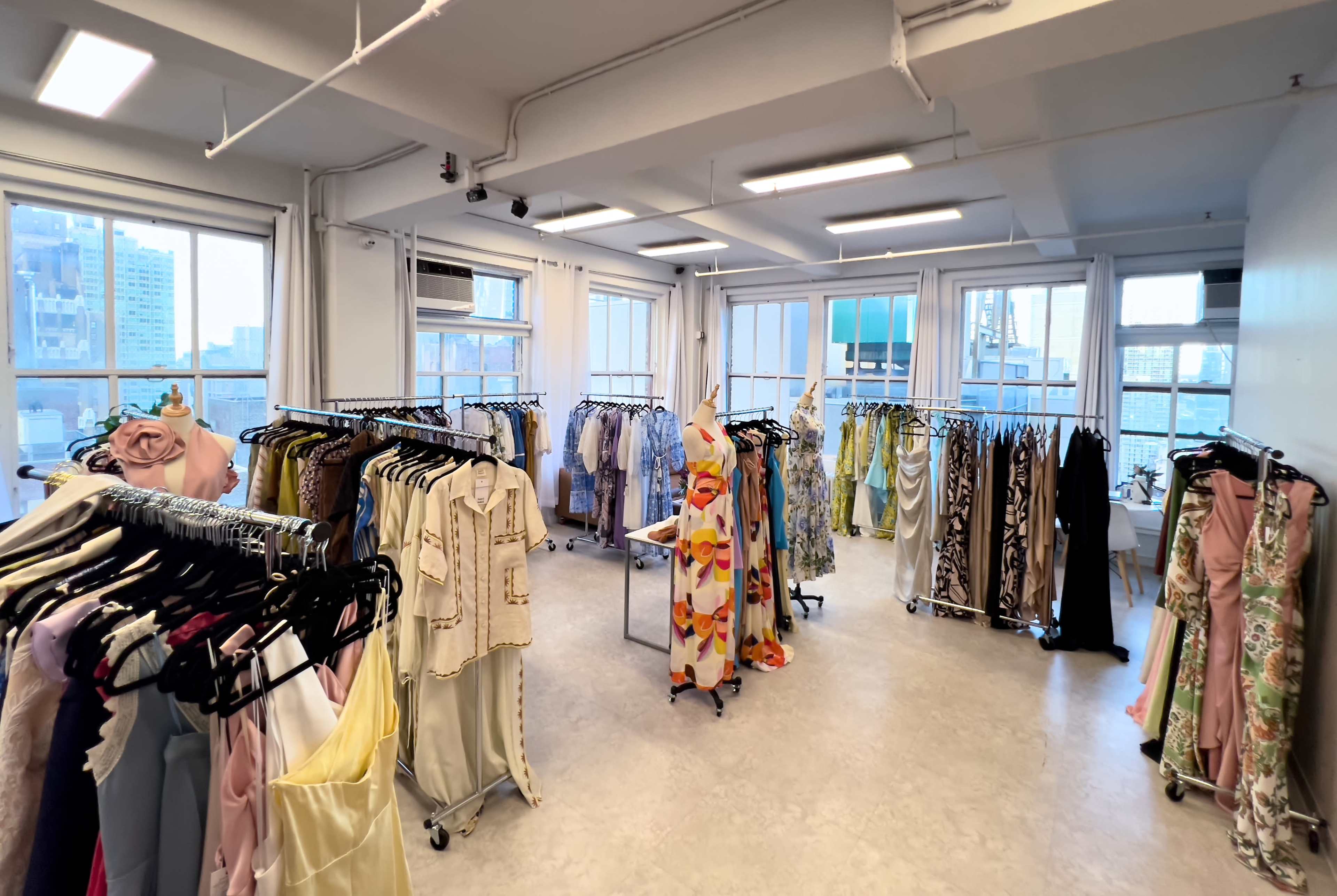A spacious clothing showroom with racks of dresses and garments arranged neatly in a well-lit room.