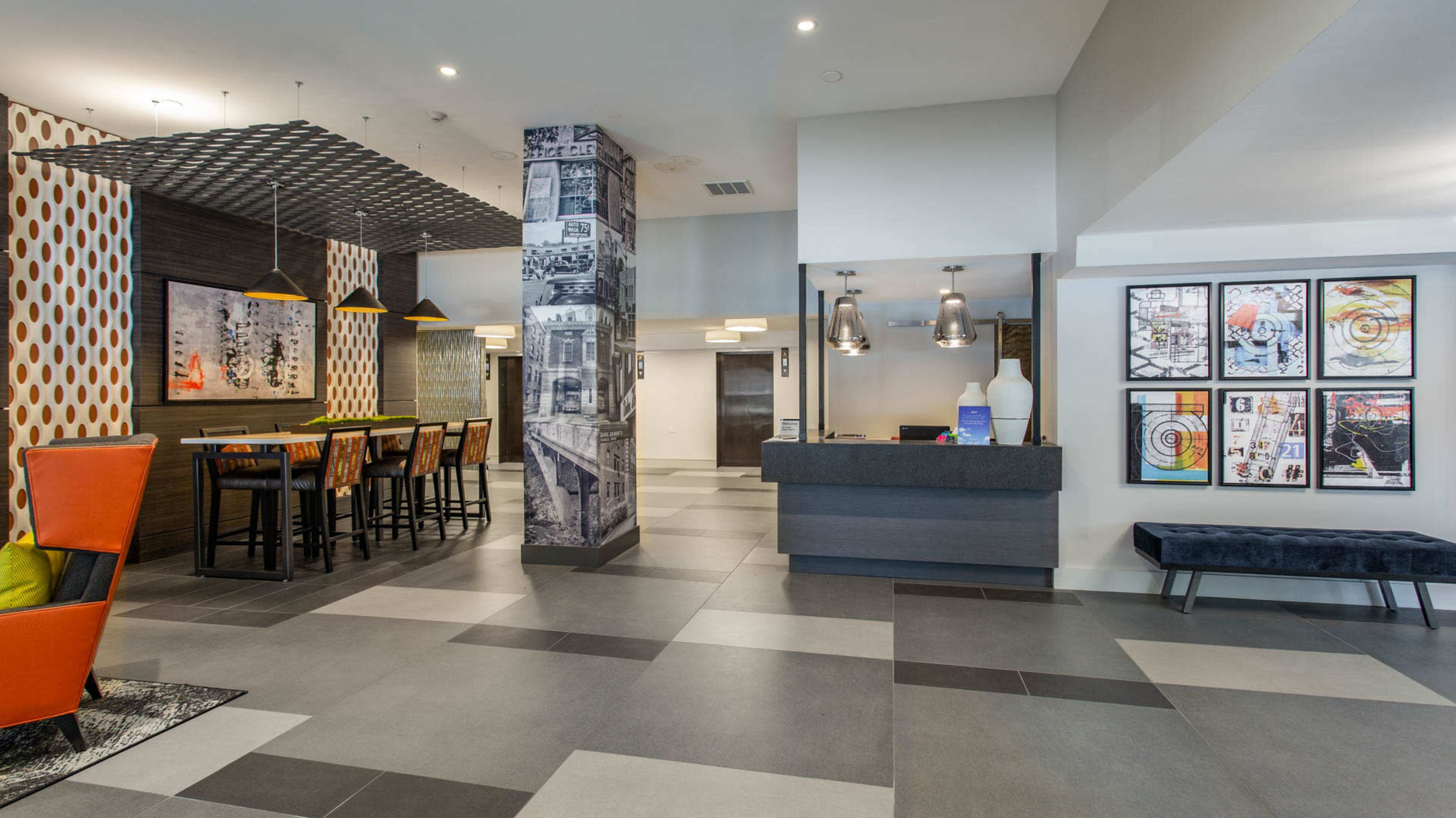 A modern lobby area with a reception desk, seating arrangements, and decorative wall art.