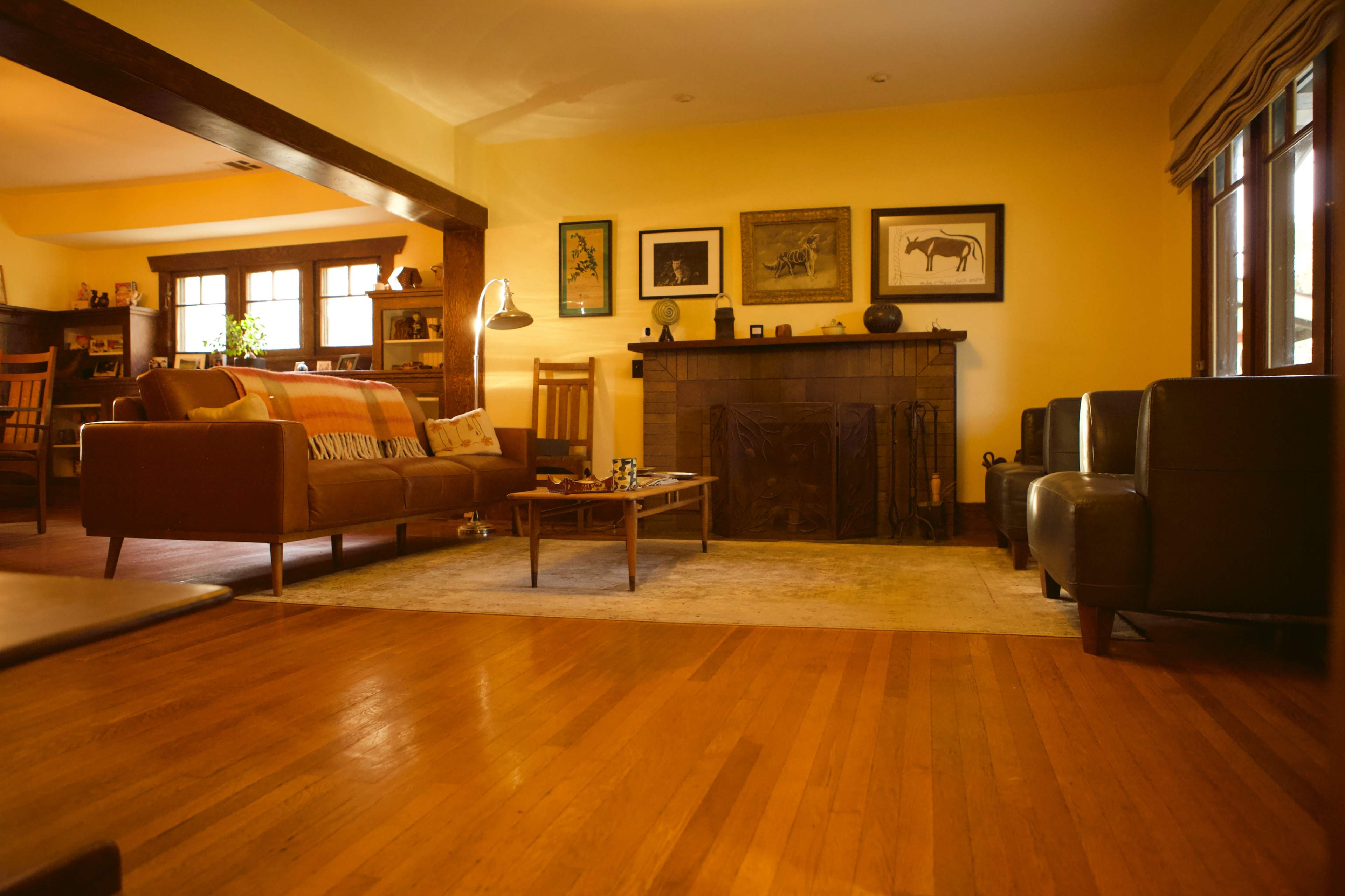 The image features a cozy living room with hardwood floors, a fireplace, and a mix of seating arrangements, including a sofa and armchairs.