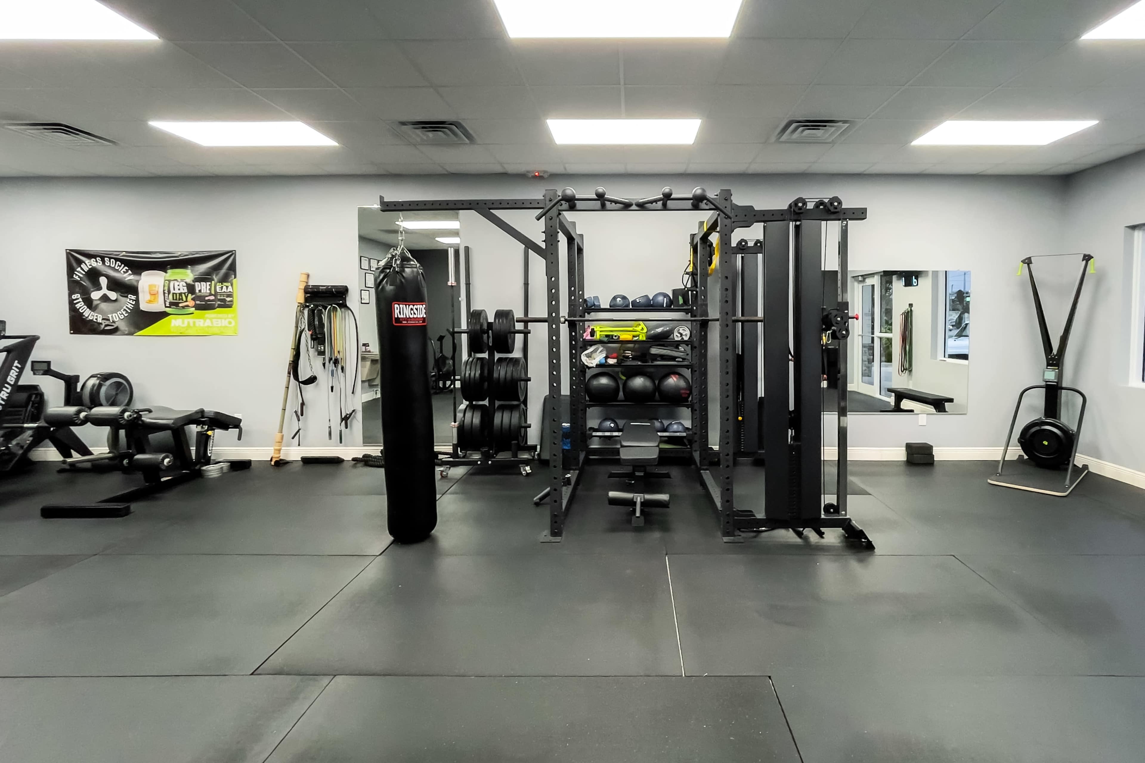 A well-equipped gym featuring weightlifting equipment, a boxing bag, and a cable machine in a spacious, well-lit environment.