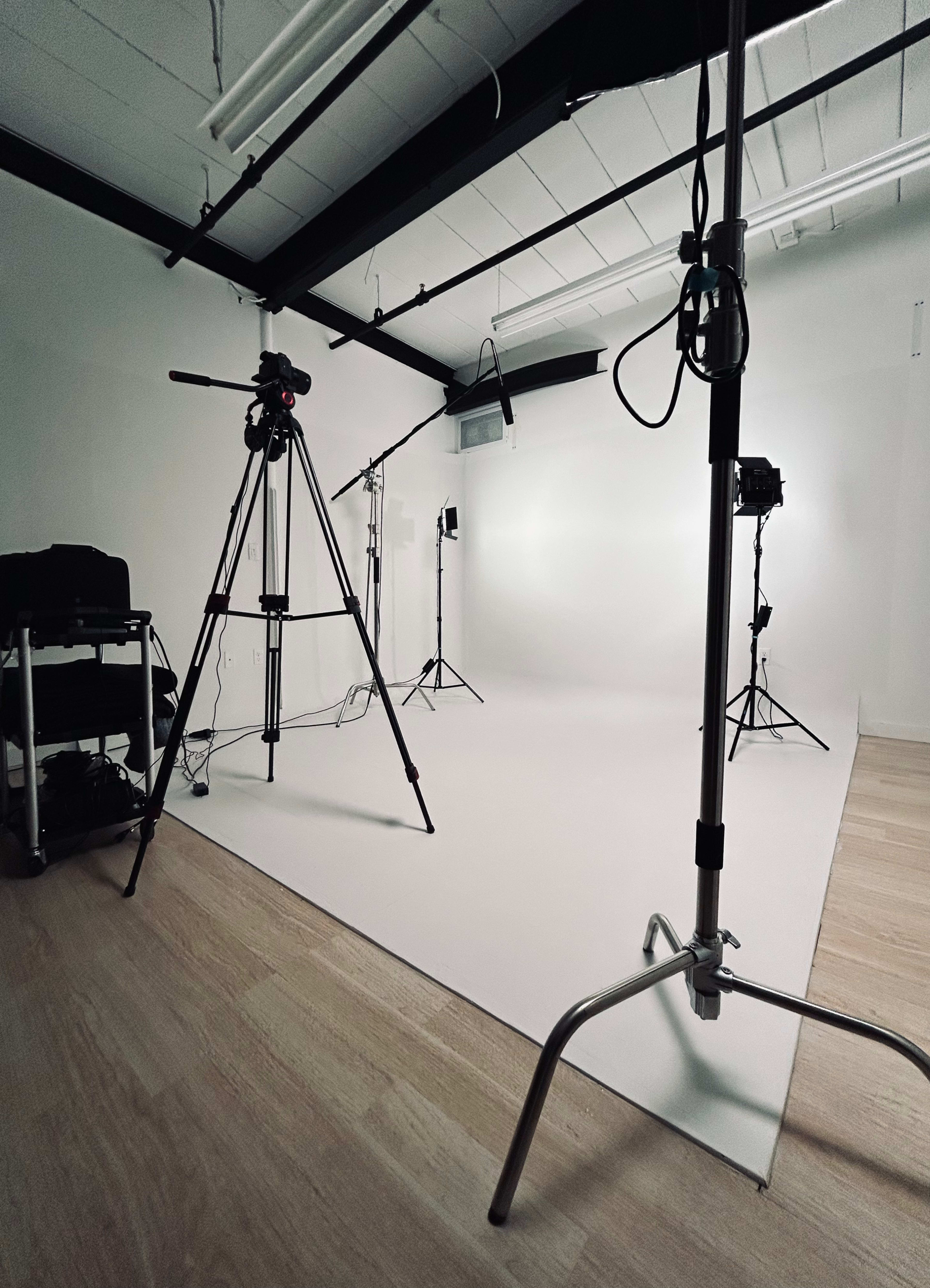 A photography studio set up with tripods, lighting equipment, and a clean white backdrop.