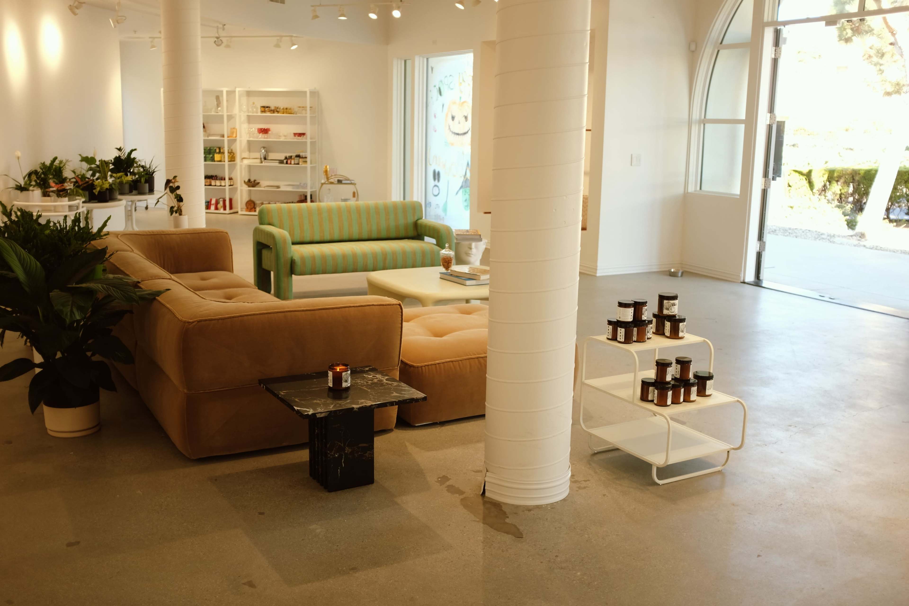 A modern interior space with various seating options, including a green-striped sofa and a beige sectional, alongside a small side table and decorative candles.