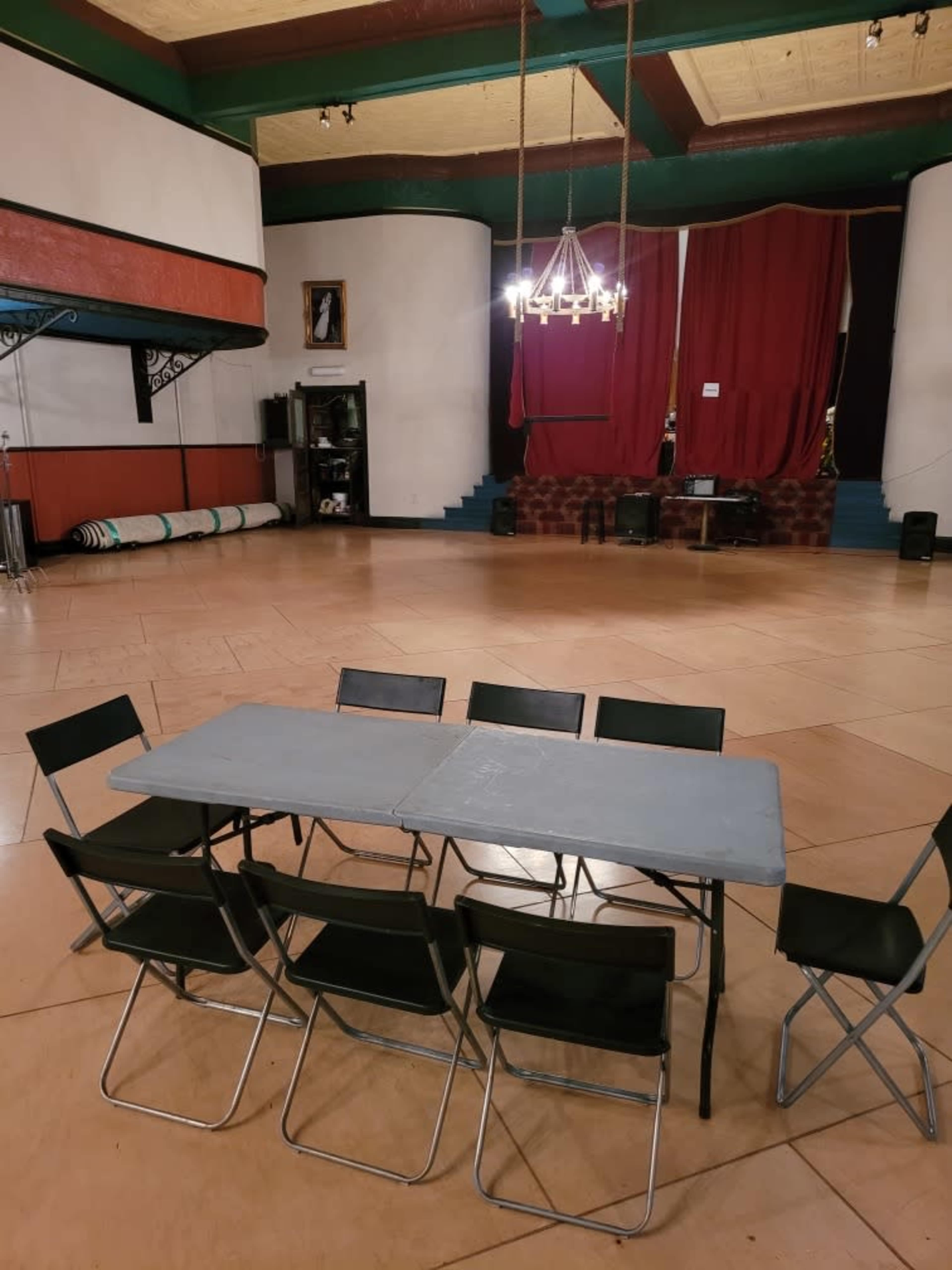 A spacious room with a large, empty floor and a simple table surrounded by six chairs in the center.