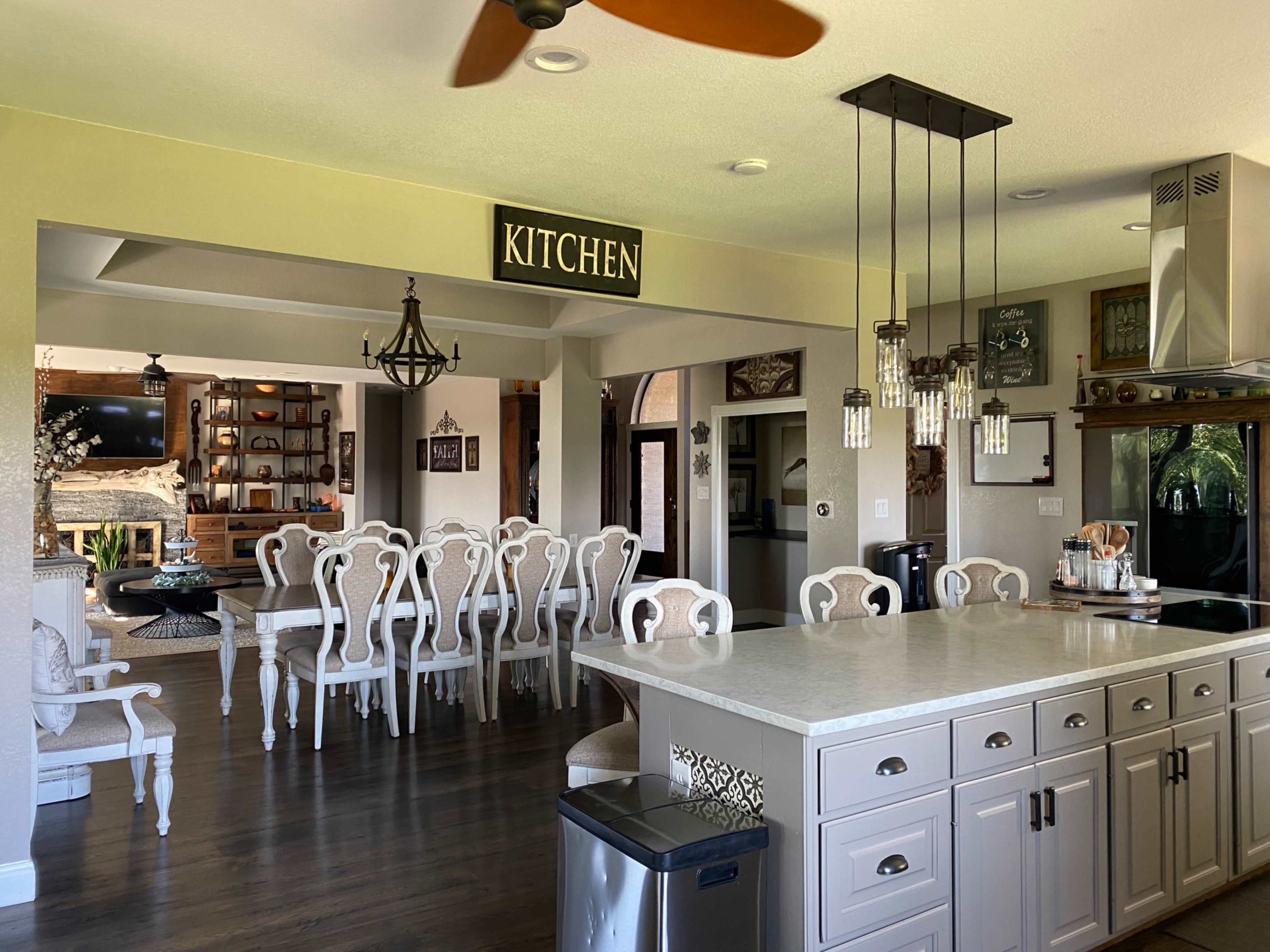 A spacious kitchen and dining area with a large island, elegant dining table, and a sign labeled "KITCHEN" above the entryway.