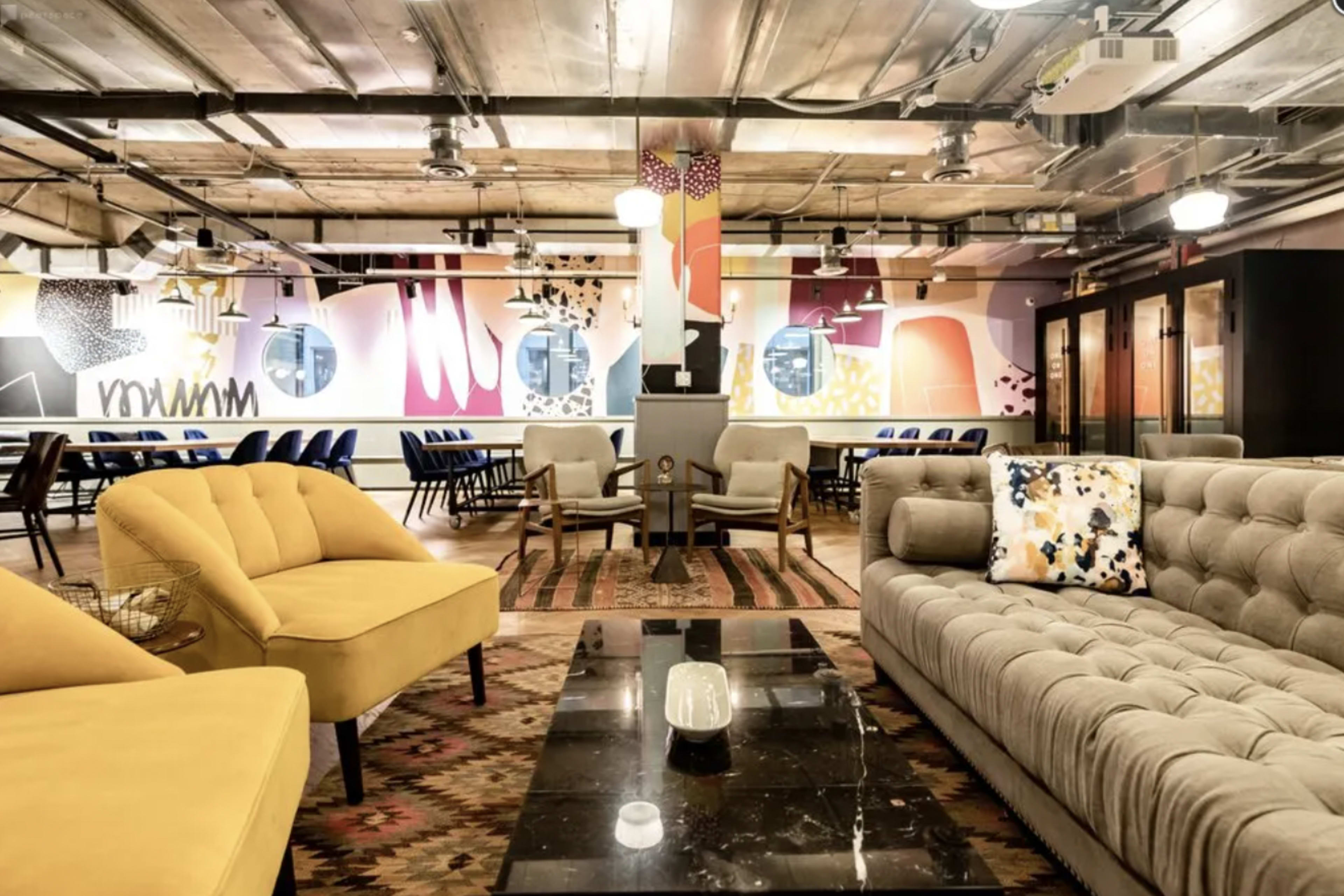 A modern co-working space featuring a mix of colorful wall art, stylish furniture, and a spacious seating area.