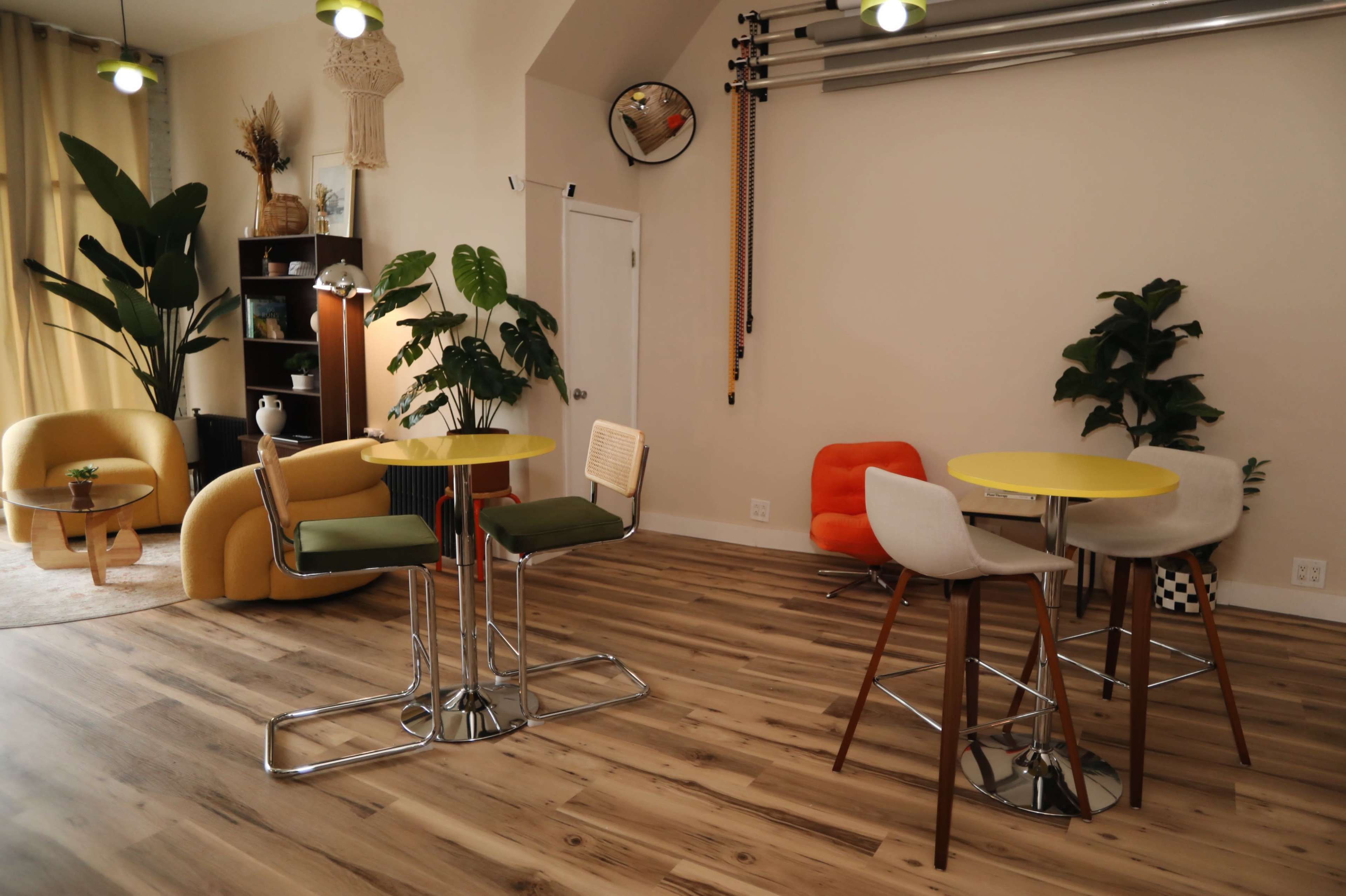 The image displays a modern, functional interior space featuring seating areas with tables, plants, and decorative elements.