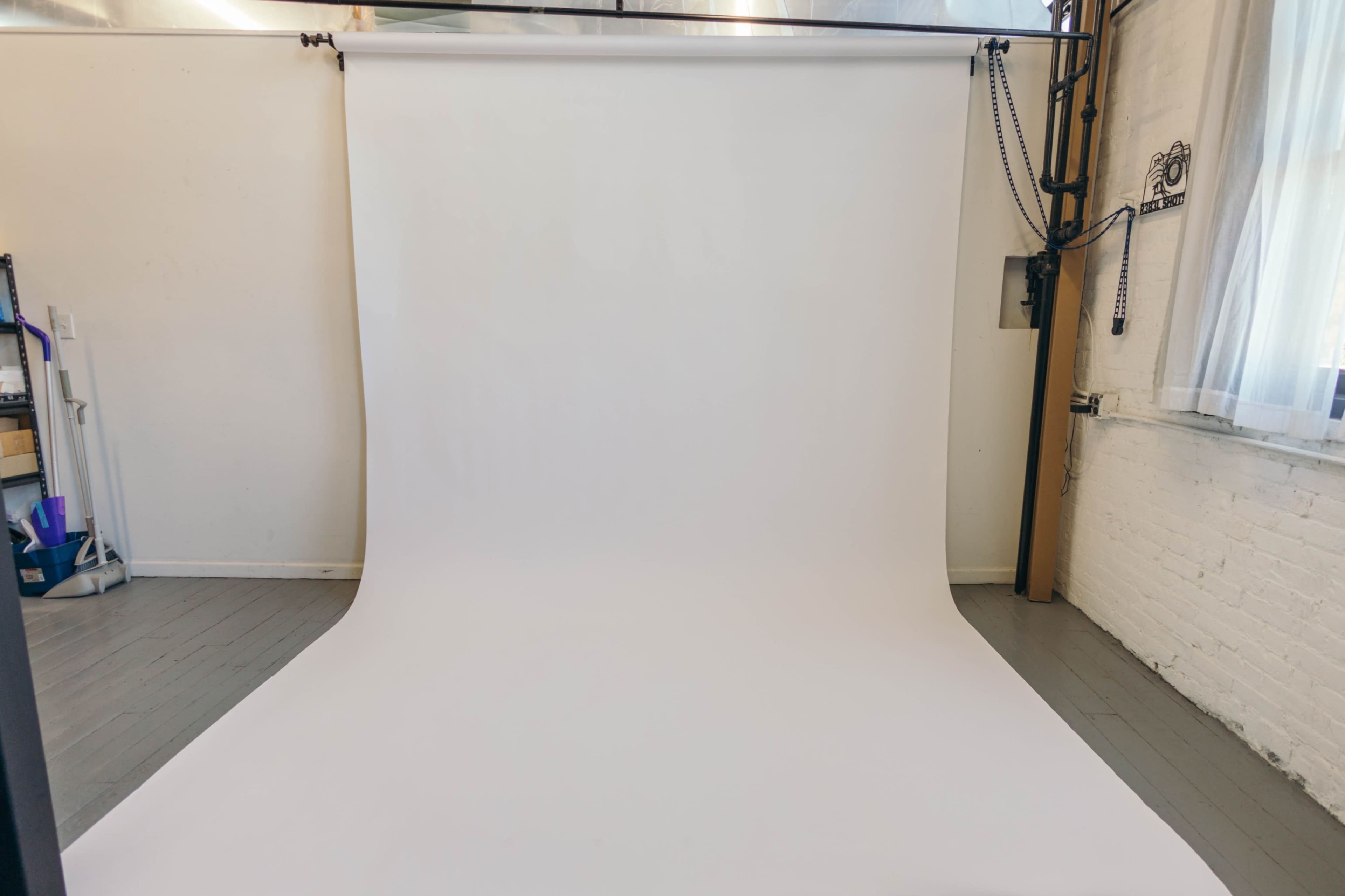 The image shows a white photo backdrop set up in a studio with minimalist surroundings.
