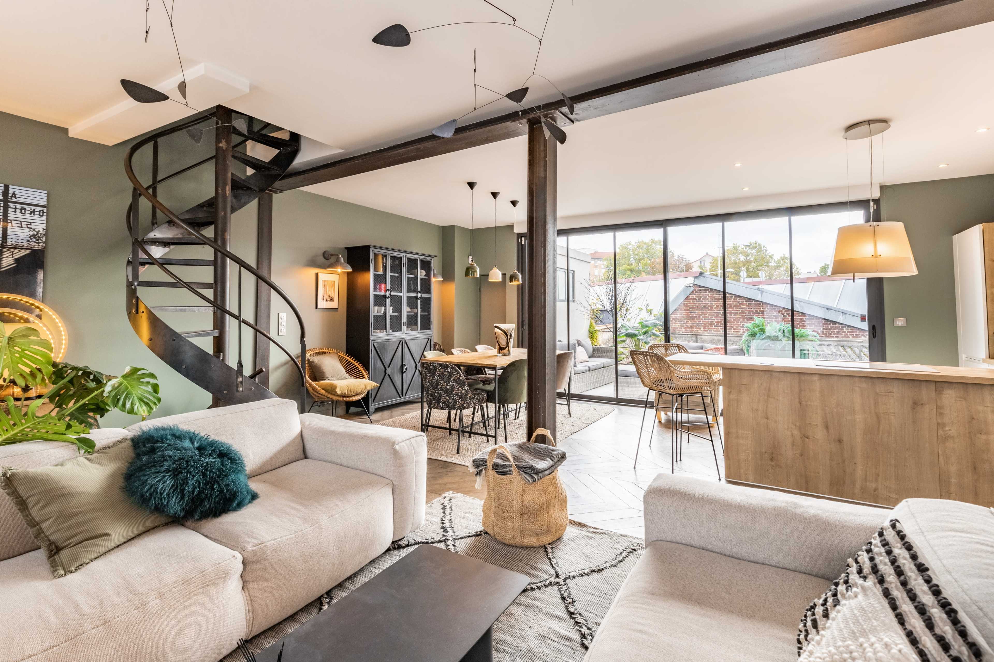A modern living space featuring a spiral staircase, large windows, and a combination of seating areas with a dining table in the background.