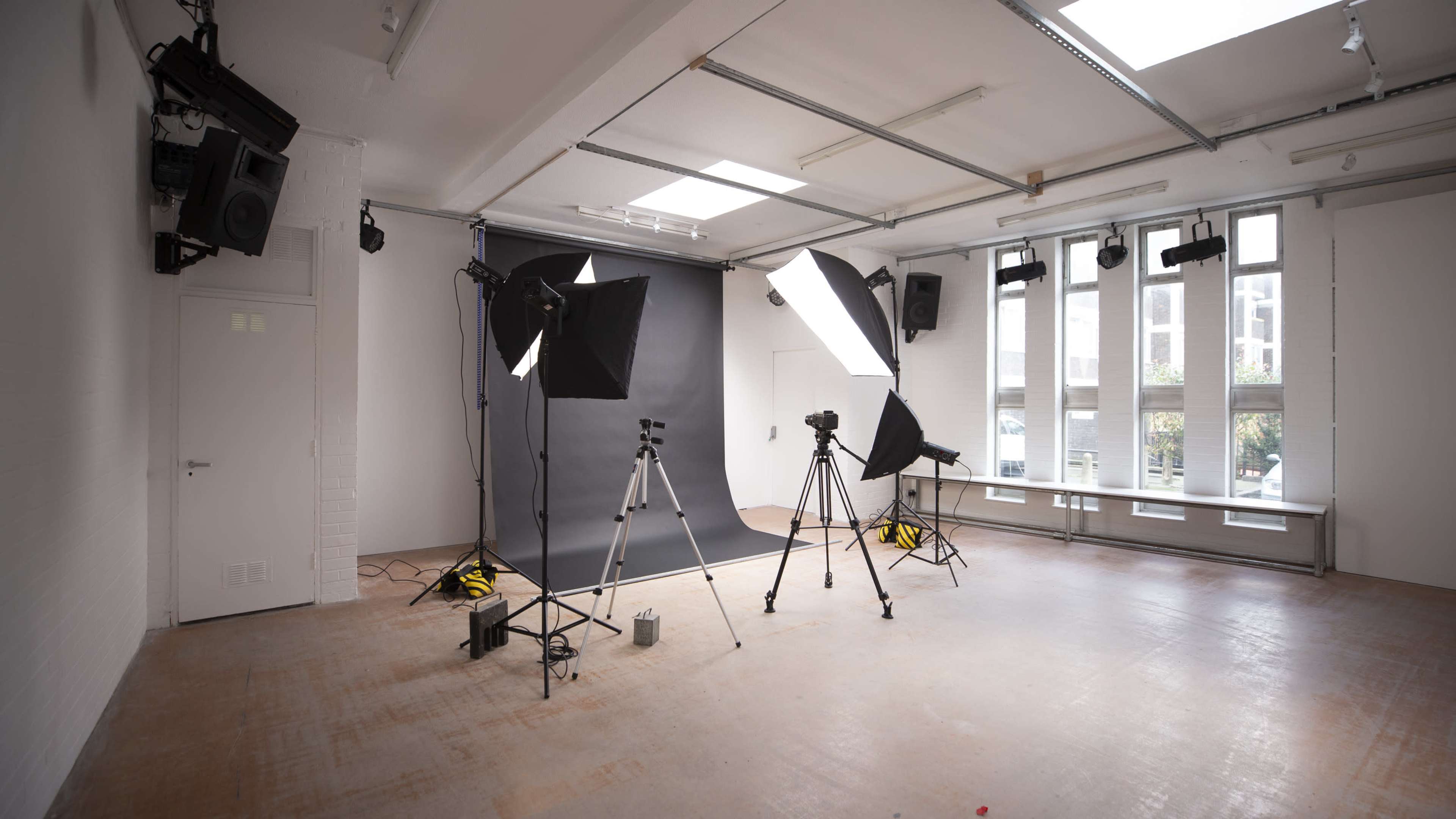 A photo studio equipped with lighting equipment, tripods, and a dark backdrop.