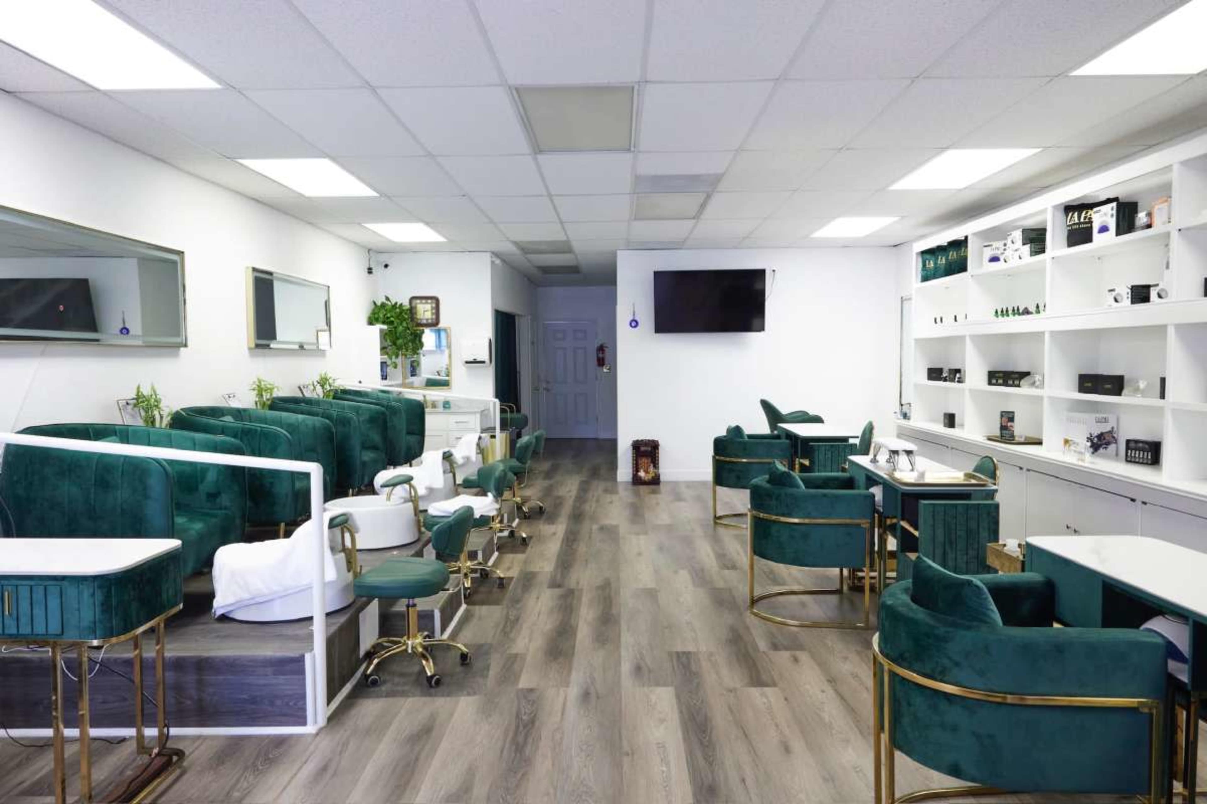 The image shows a spacious salon with green furniture, treatment stations on the left, and white shelves displaying products on the right.