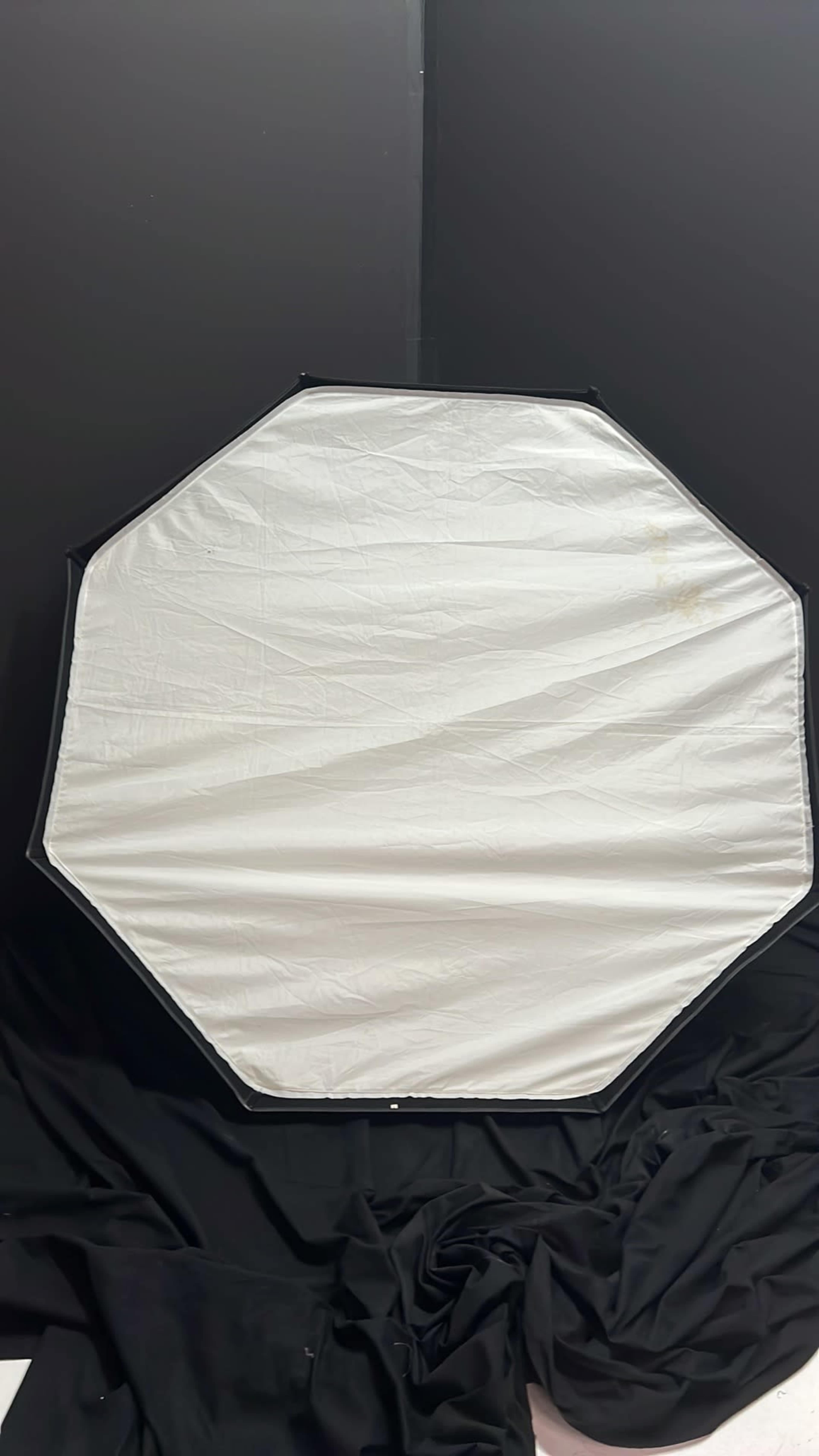 The image shows an octagonal reflector covered with a white fabric, placed against a black background.
