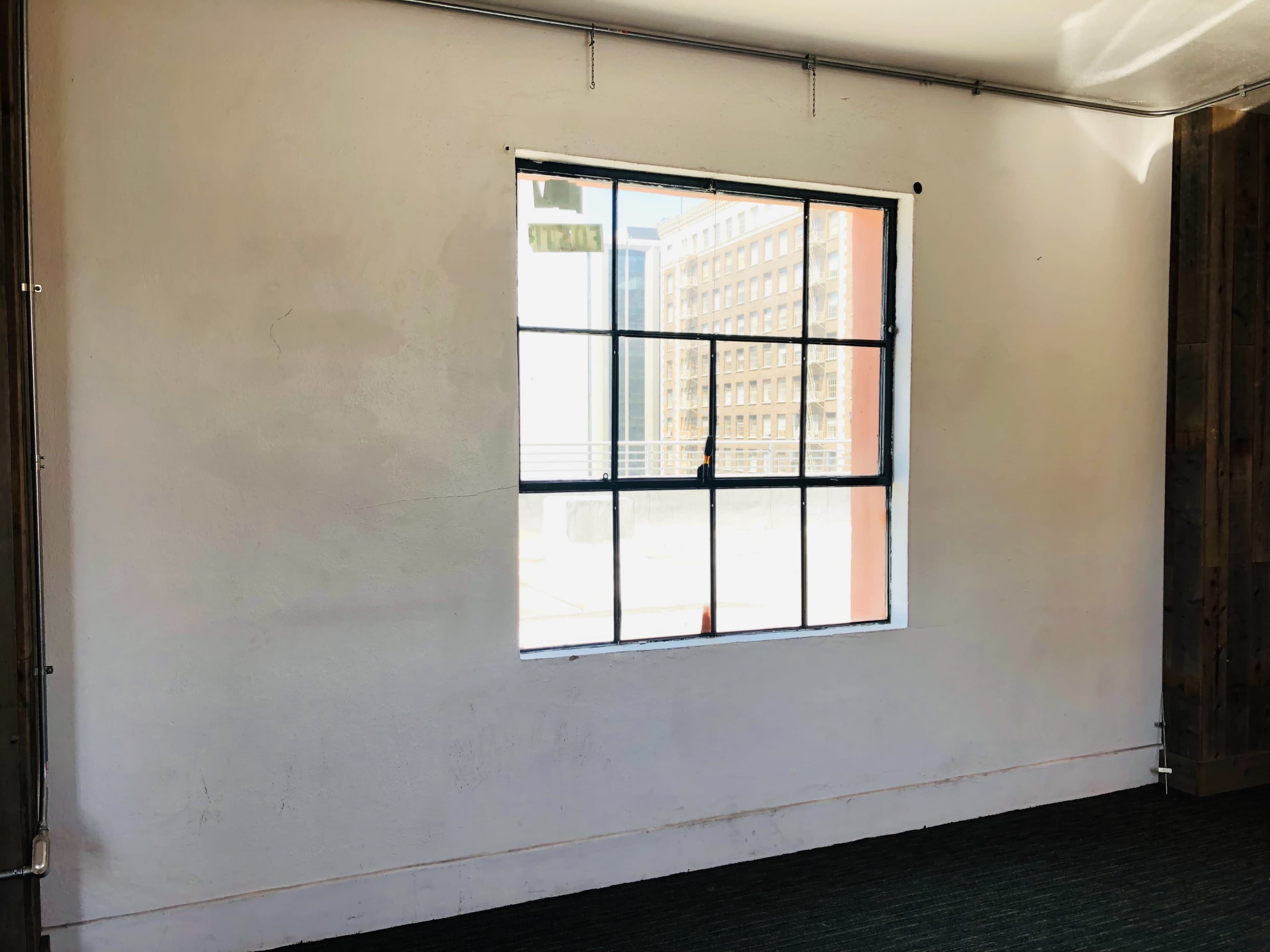 A plain white wall with a large rectangular window allows natural light to enter the room.