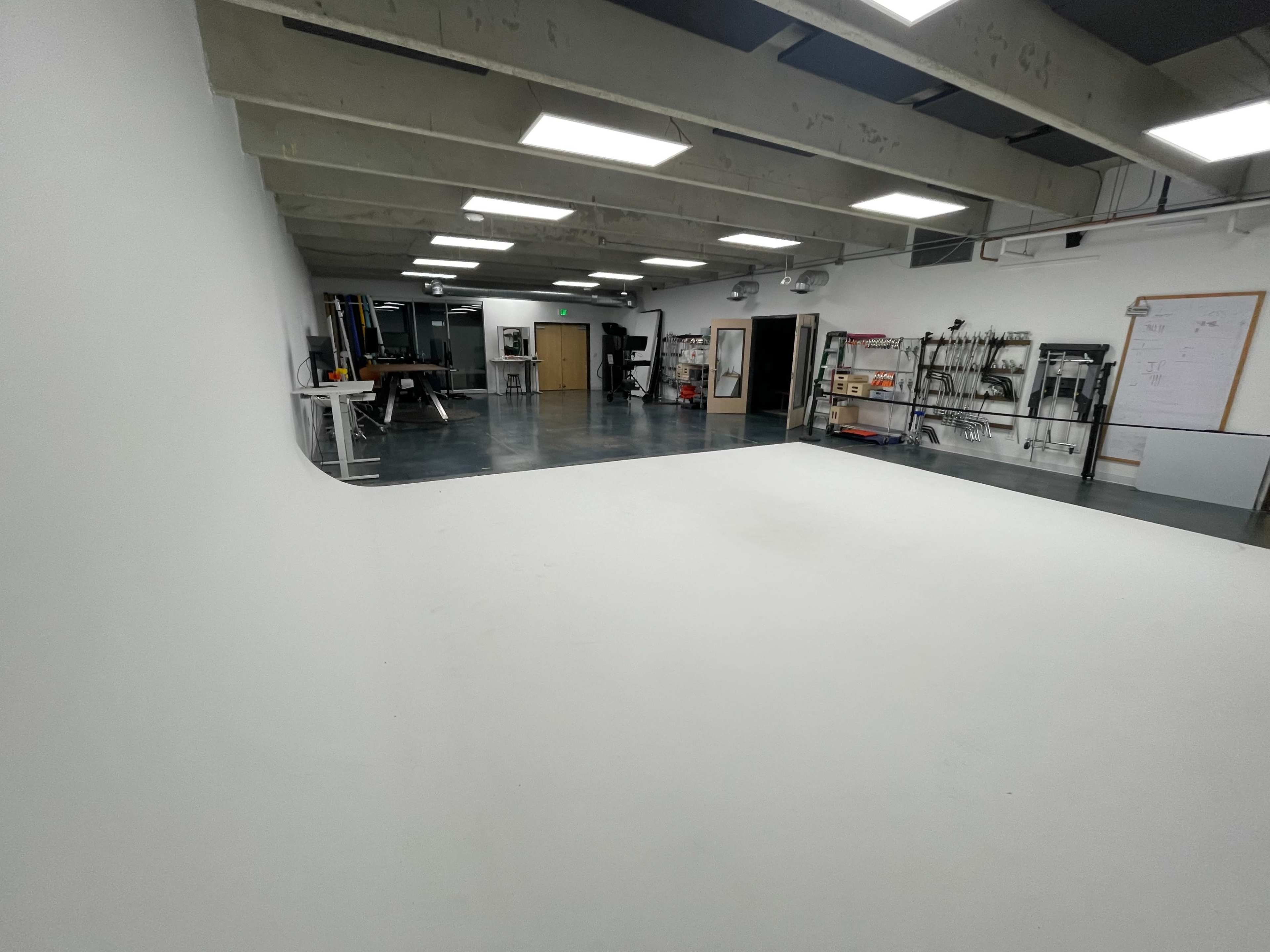 A spacious studio with a white backdrop and various equipment along the walls.