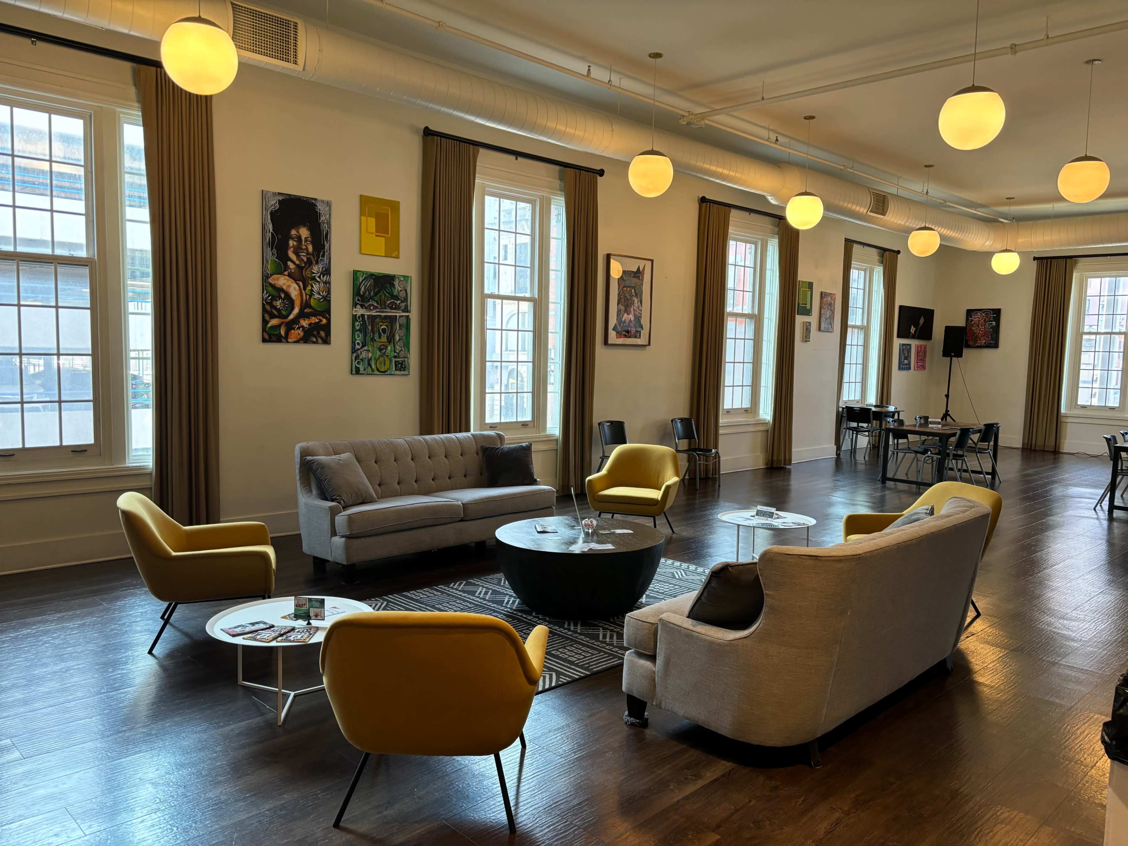 A spacious lounge area furnished with gray and yellow seating, a black coffee table, and various framed artworks on the walls.