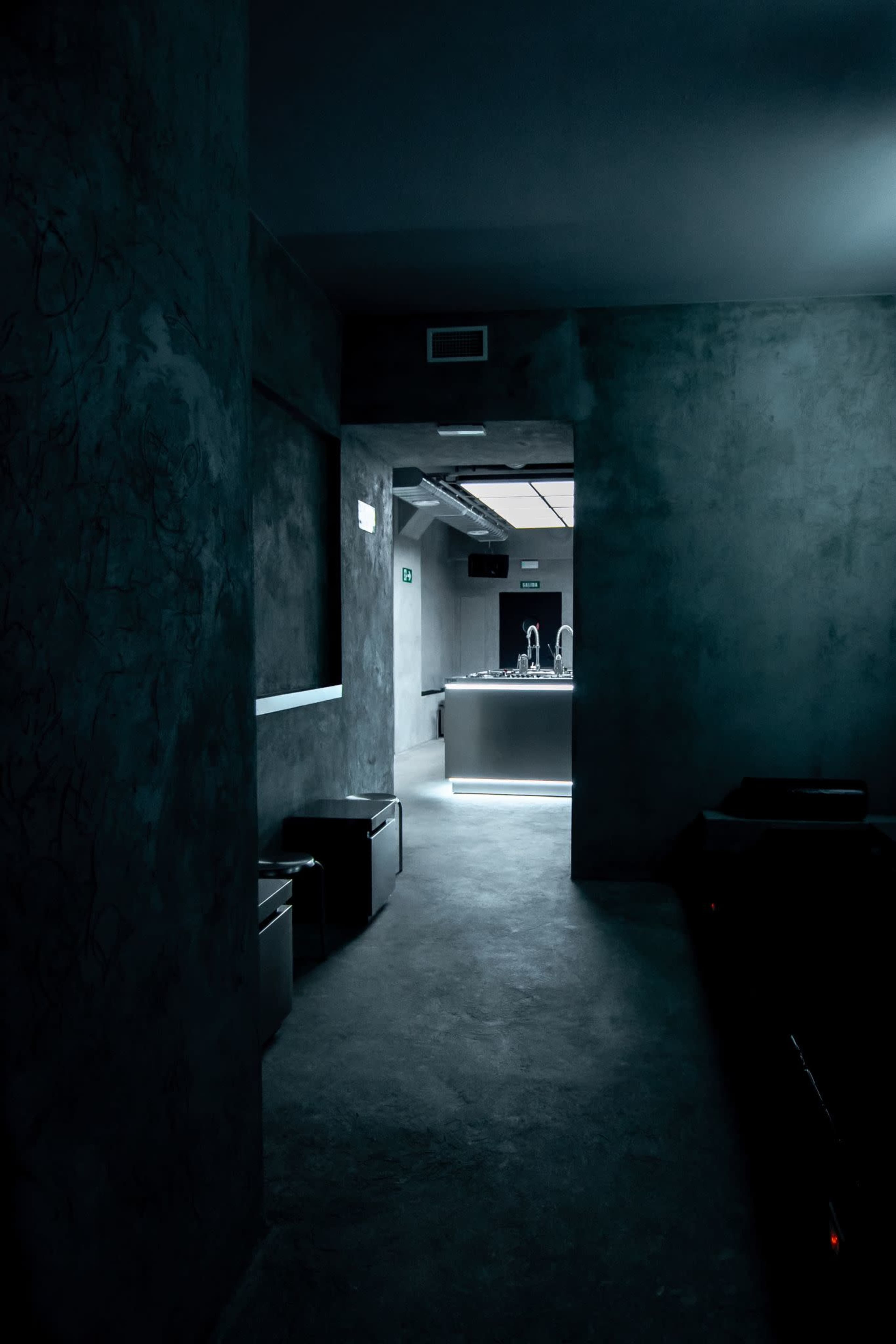 A dimly lit hallway leads to a modern bar area with a minimalist design.