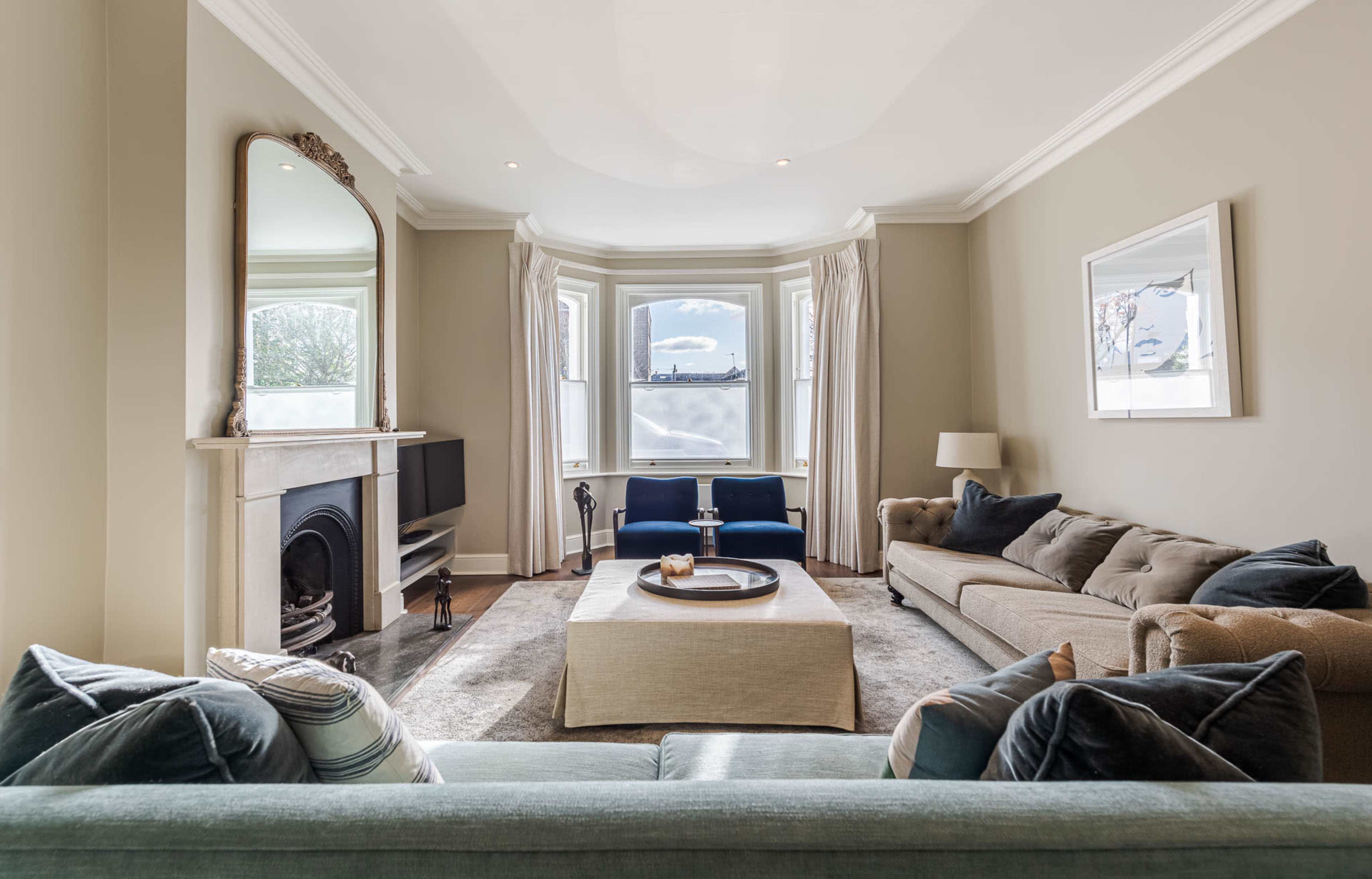 The living room features a large window with a view, a fireplace, a sofa, two blue chairs, and a coffee table in the center.